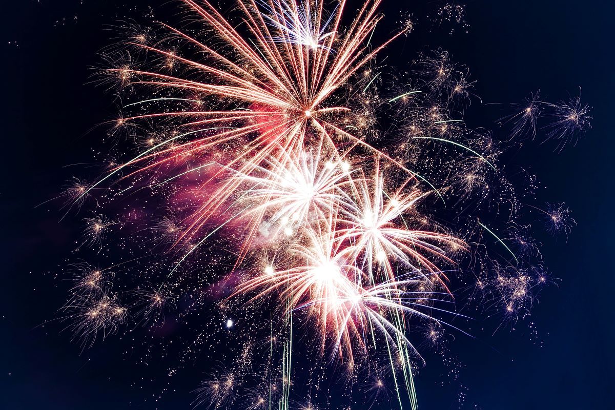 Vibrant red and white fireworks exploding against a dark night sky.