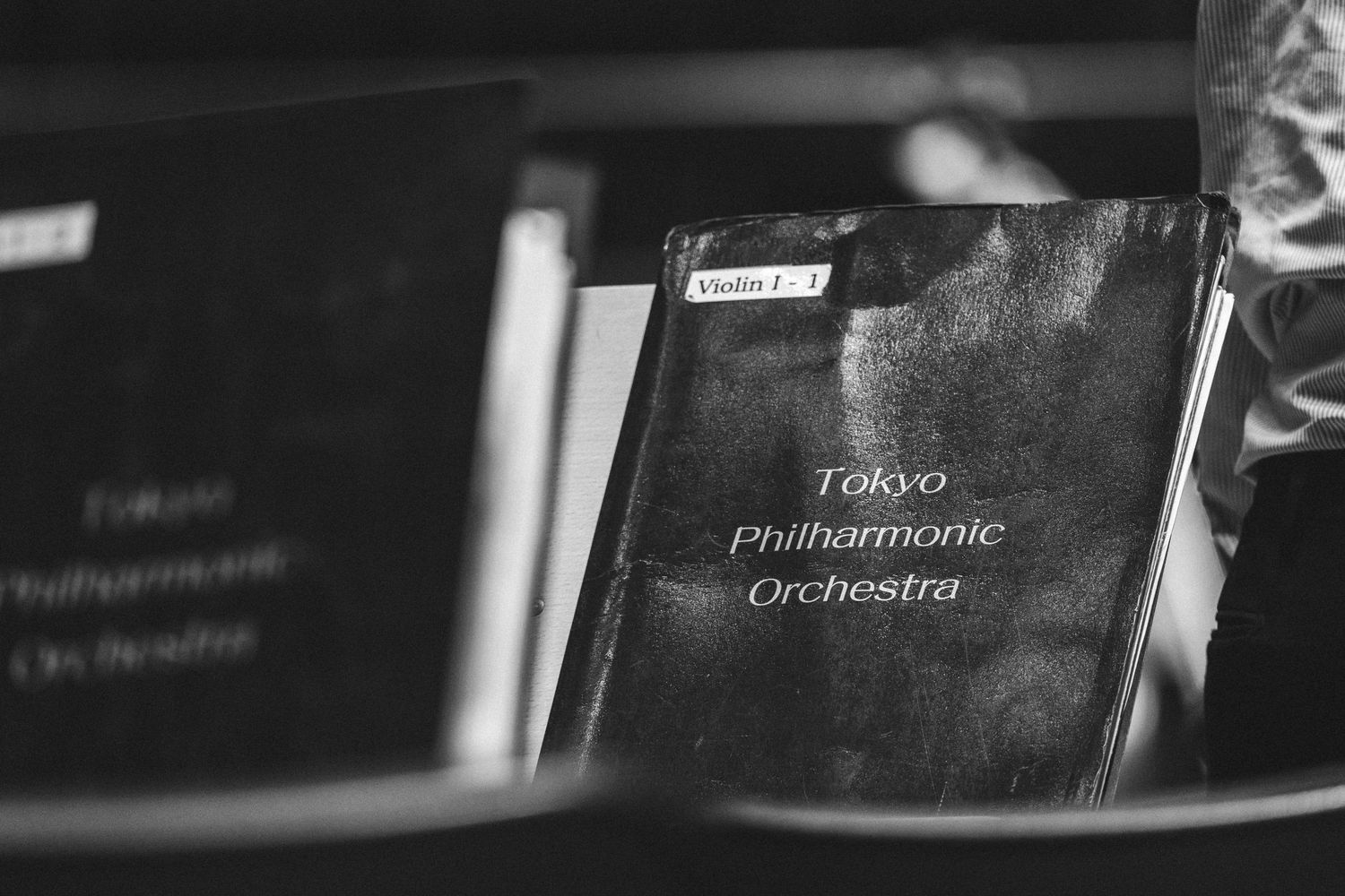 Black and white photo of Tokyo Philharmonic Orchestra violin sheet music folder on a stand.