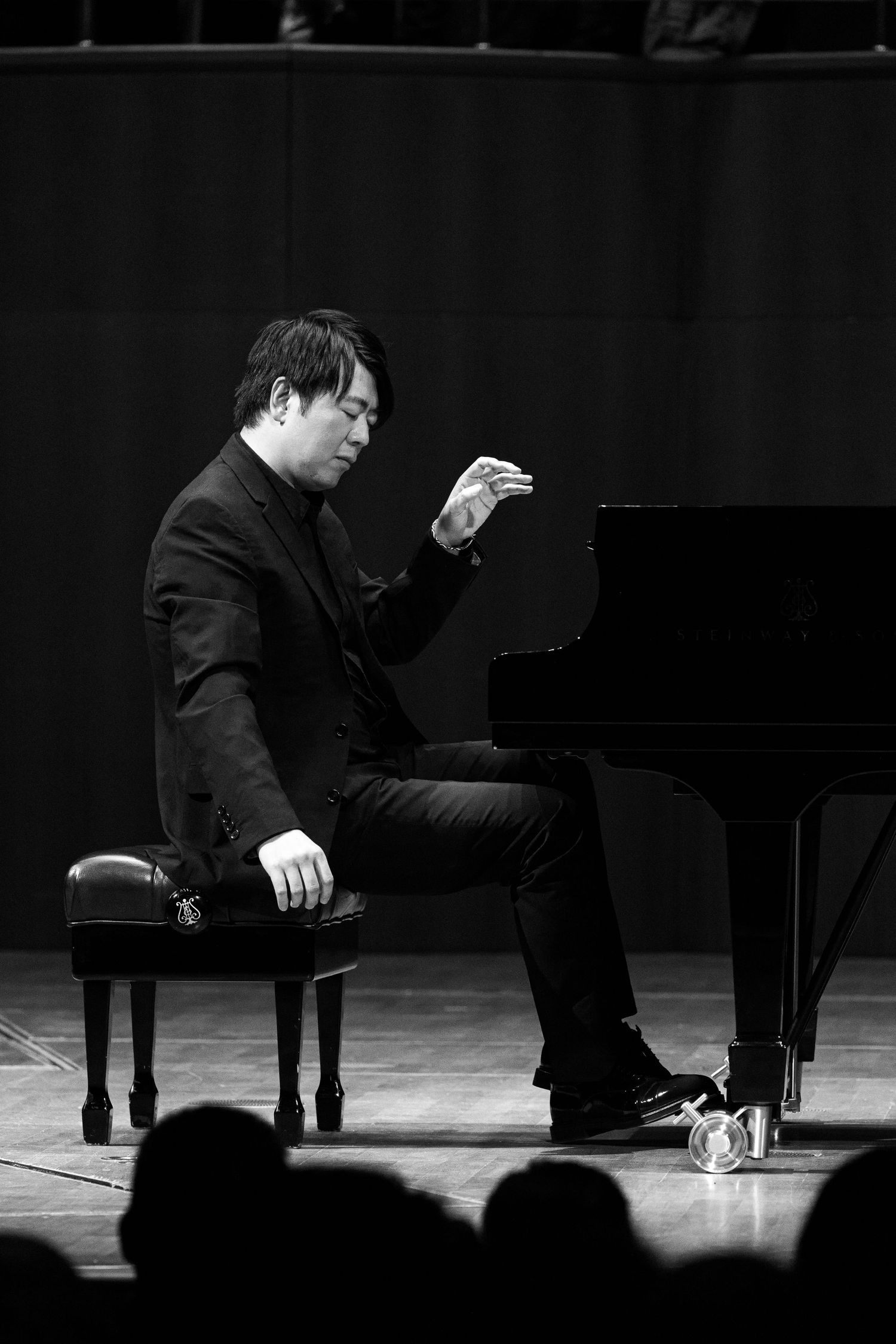 Black and white photo of a male pianist performing on stage at a grand piano concert.