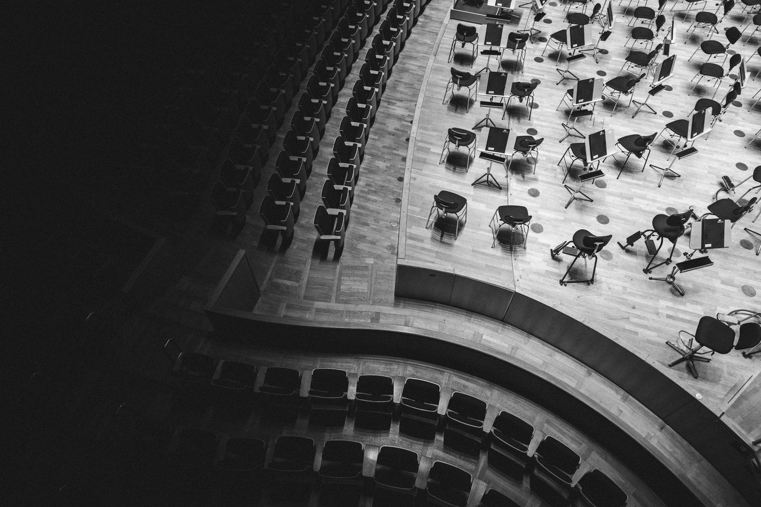 Black and white aerial view of empty chairs arranged in curved rows in a concert hall or auditorium.