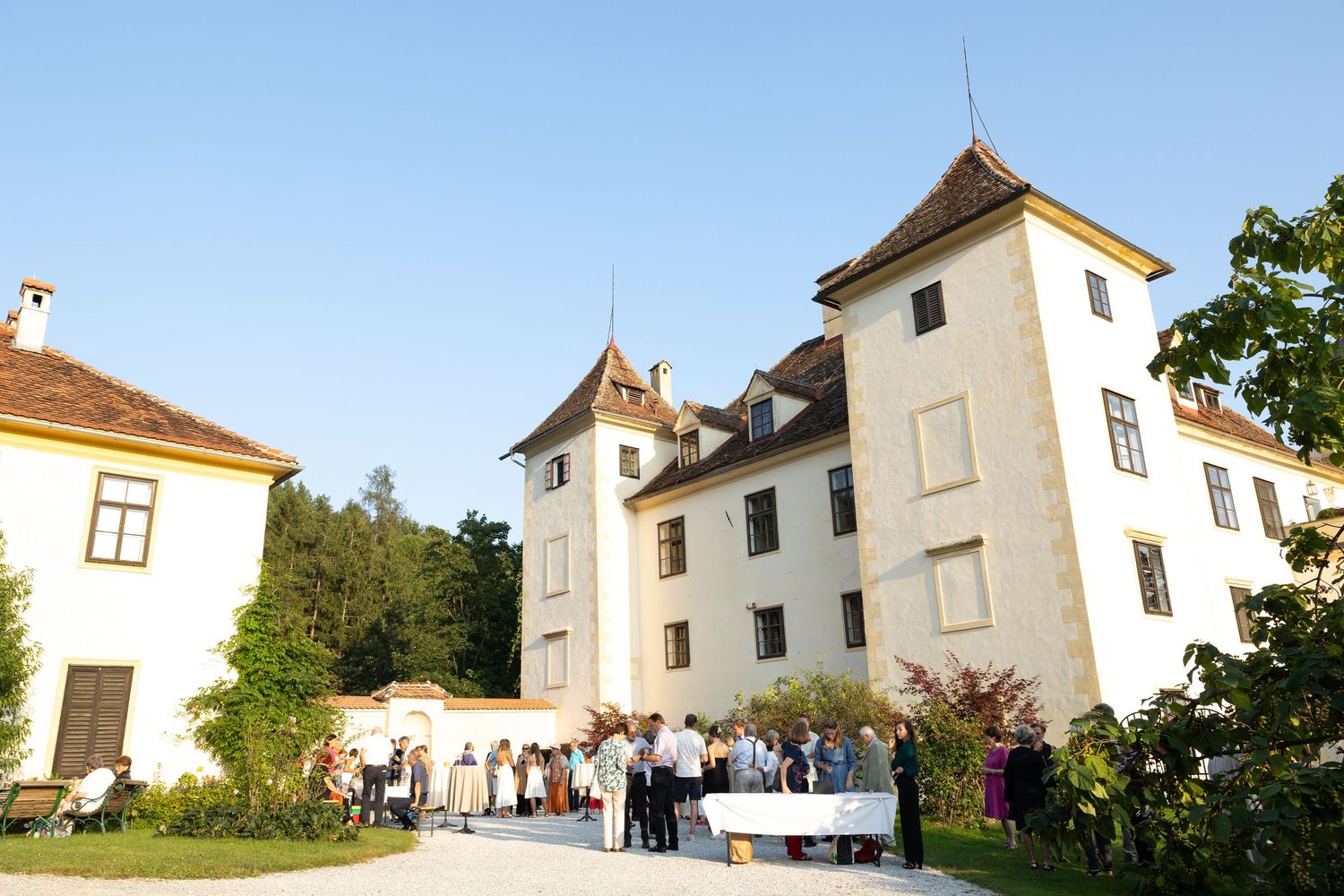 Elegant white castle venue with guests gathered outside for an event on a sunny day.