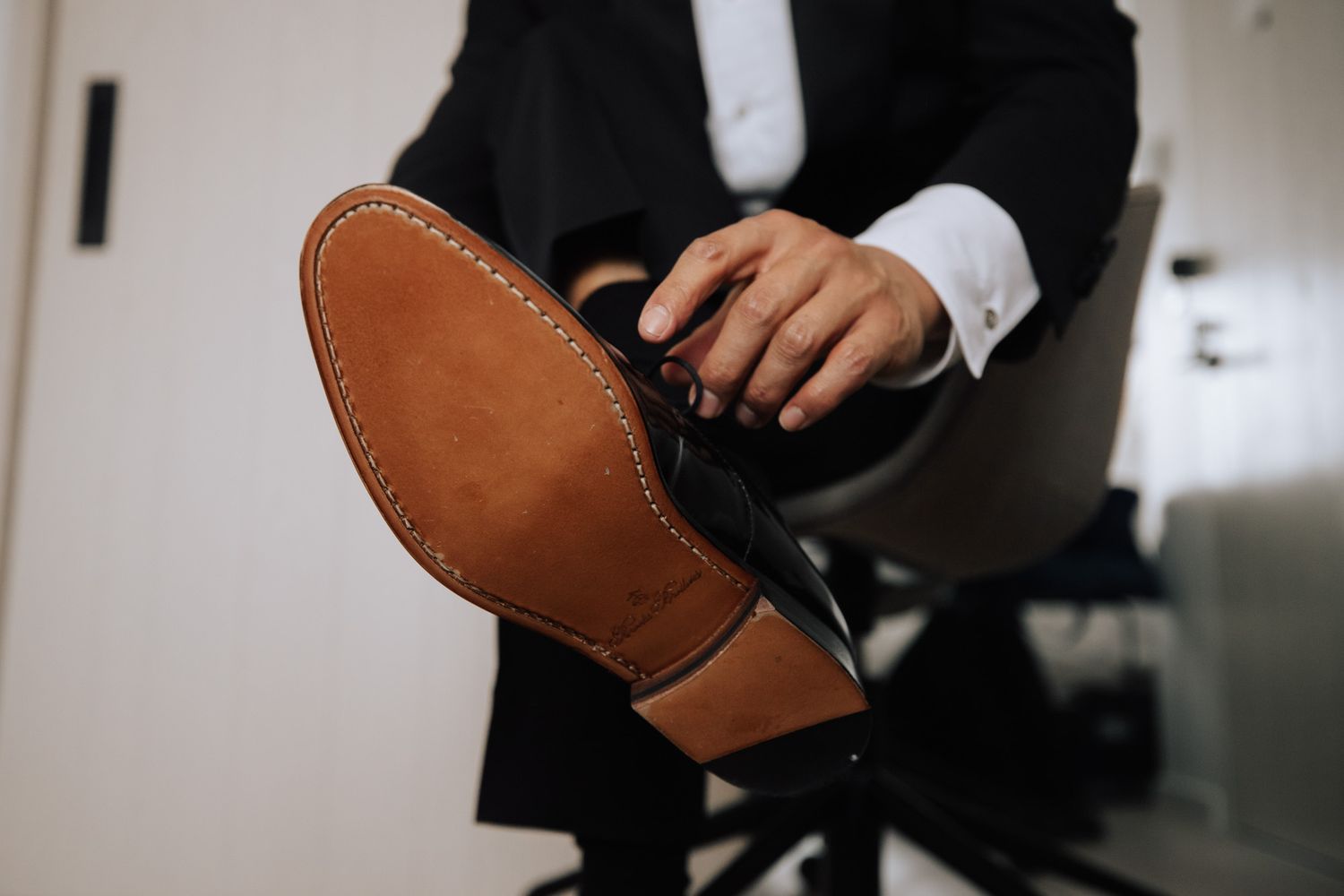 Close-up of groom polishing leather dress shoe sole before wedding ceremony.