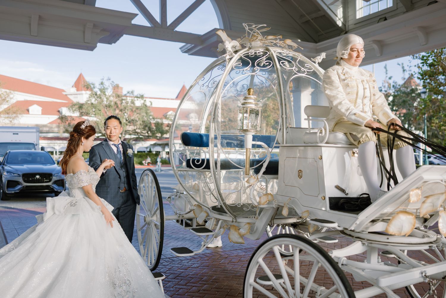 Bride and groom approach iconic Cinderella glass carriage with white horses at Disney World.