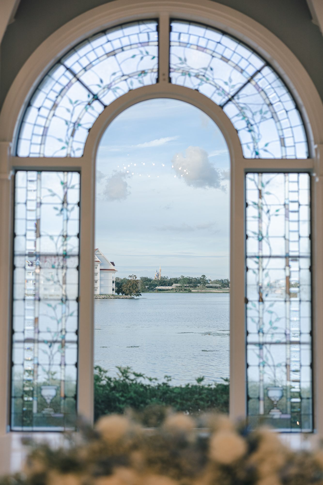 Arched stained glass window overlooking a serene waterway at a Disney wedding venue chapel.