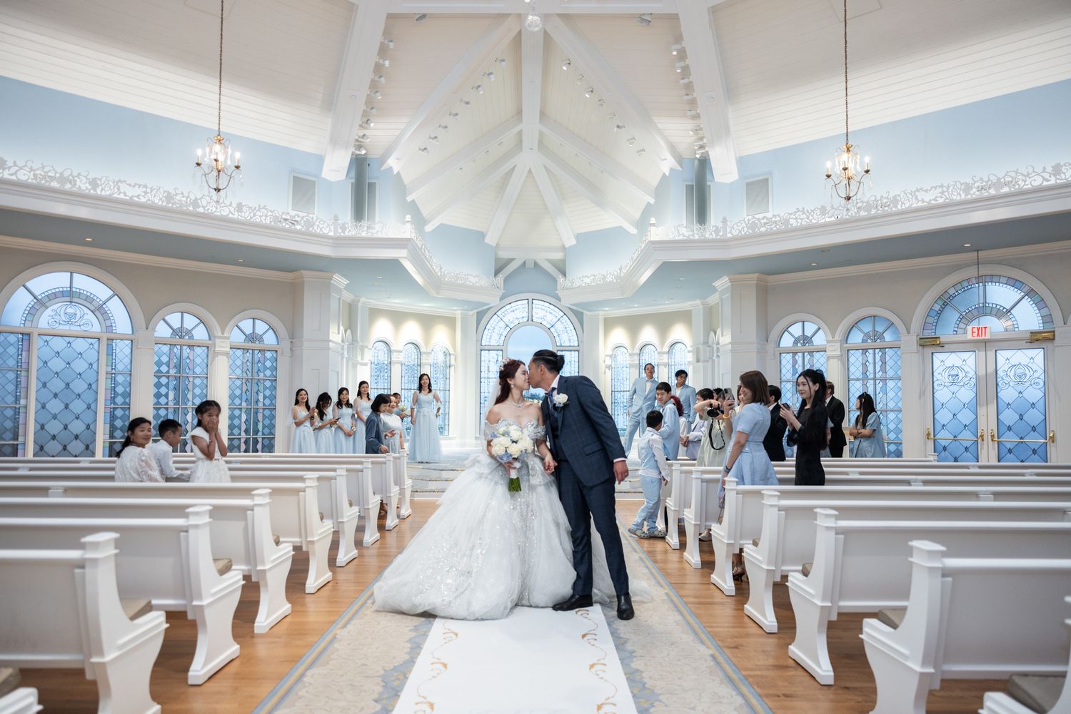 Bride and groom share first kiss at altar in stunning blue and white Disney wedding chapel.