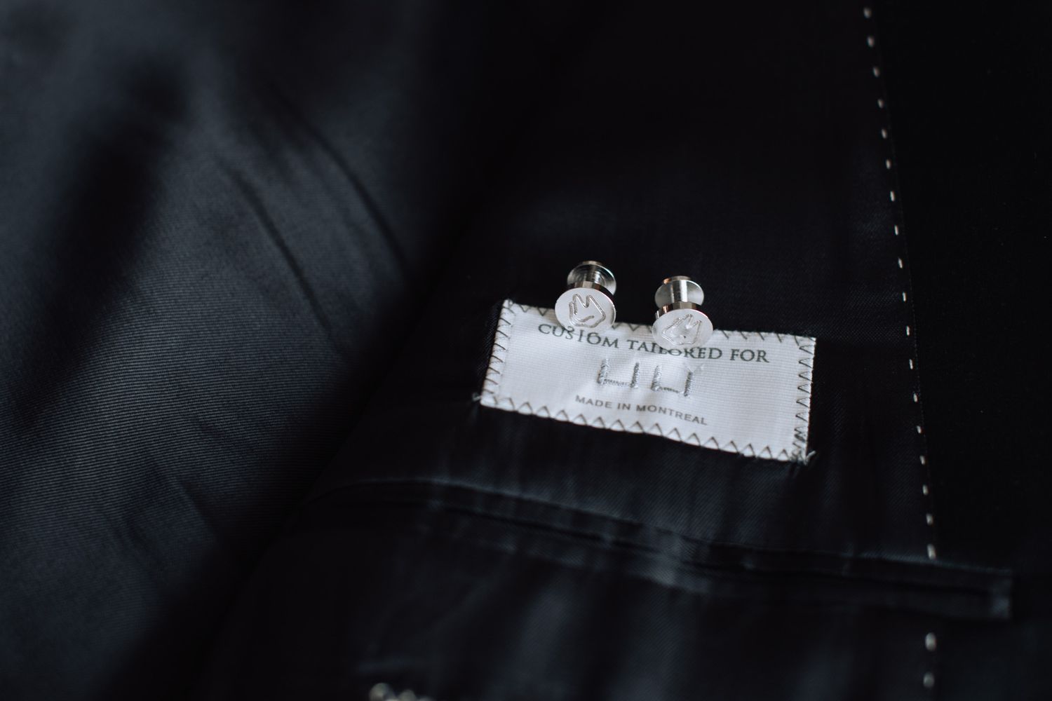 Custom tailored groom suit with silver cufflinks and personalized label inside jacket pocket.
