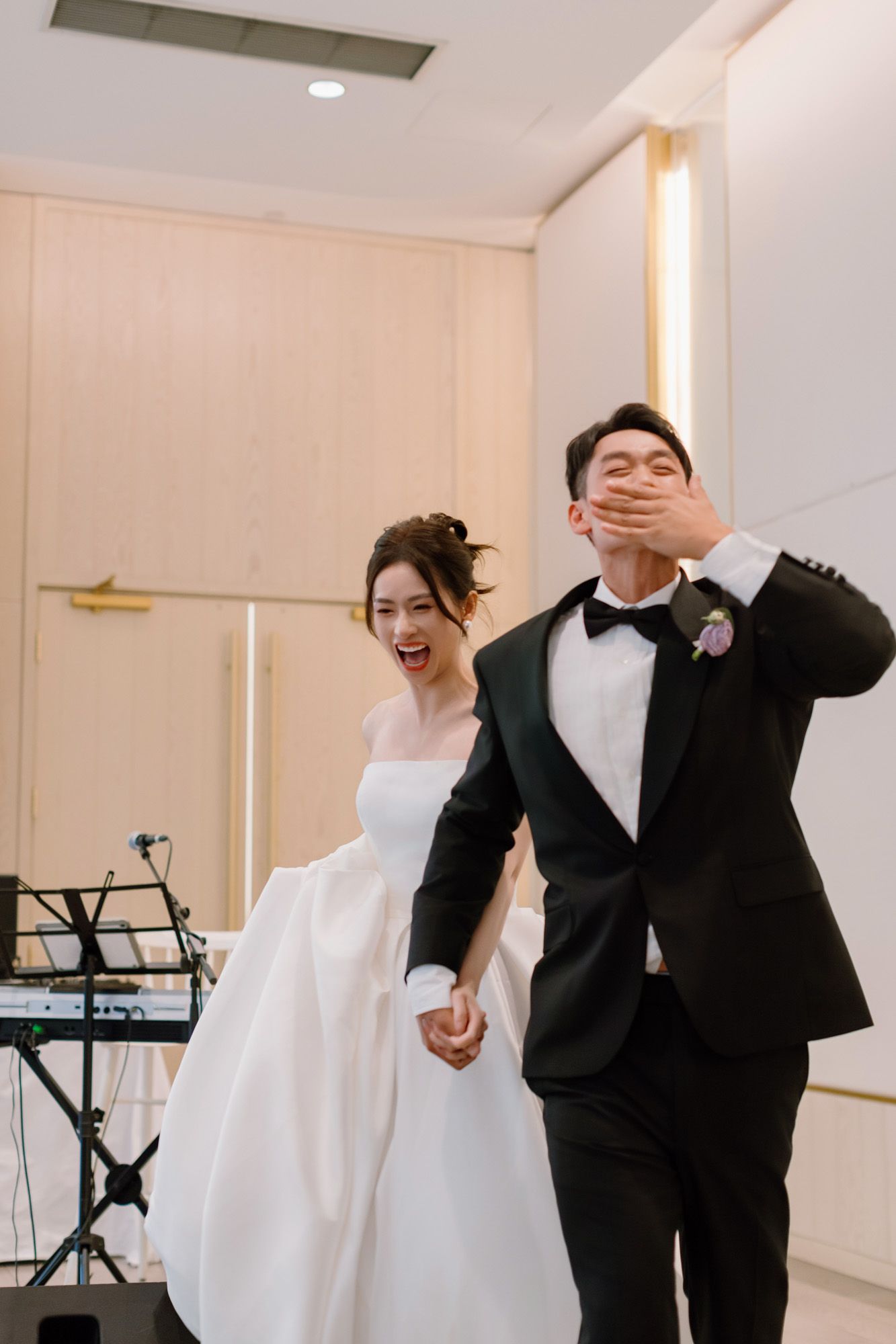 Happy bride and groom holding hands laughing during their wedding reception entrance.