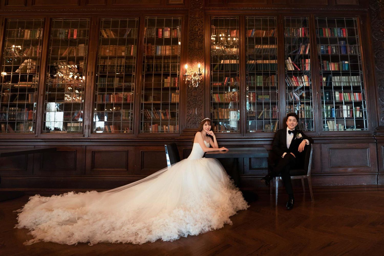 Elegant bride and groom pose in a grand wood-paneled library with floor-to-ceiling bookshelves.