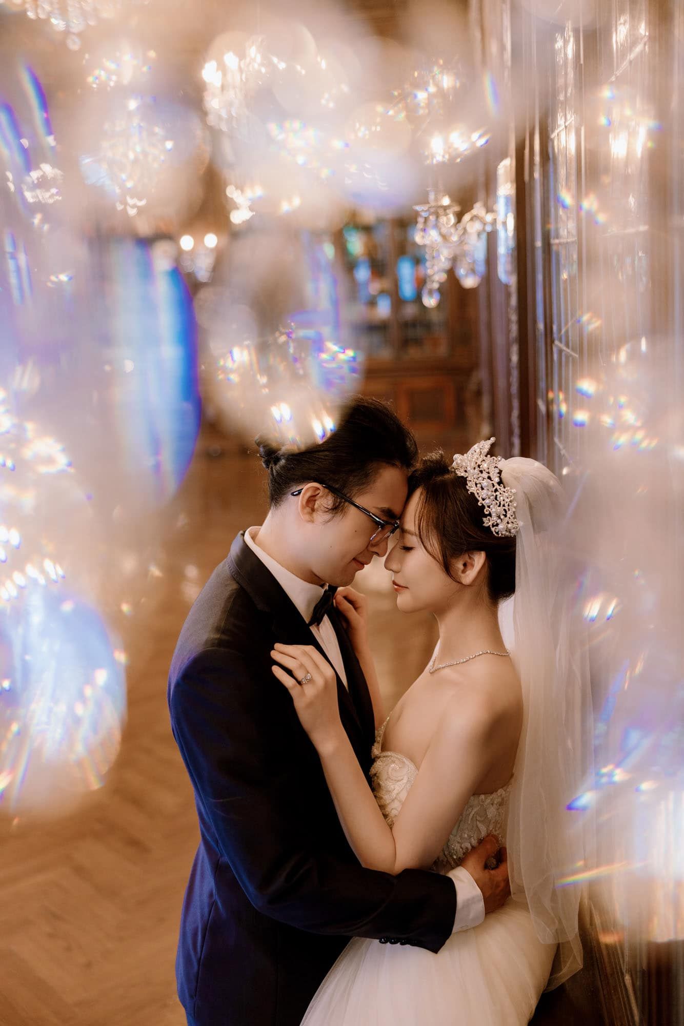 Bride and groom sharing an intimate moment surrounded by sparkling bokeh lights in a romantic setting.