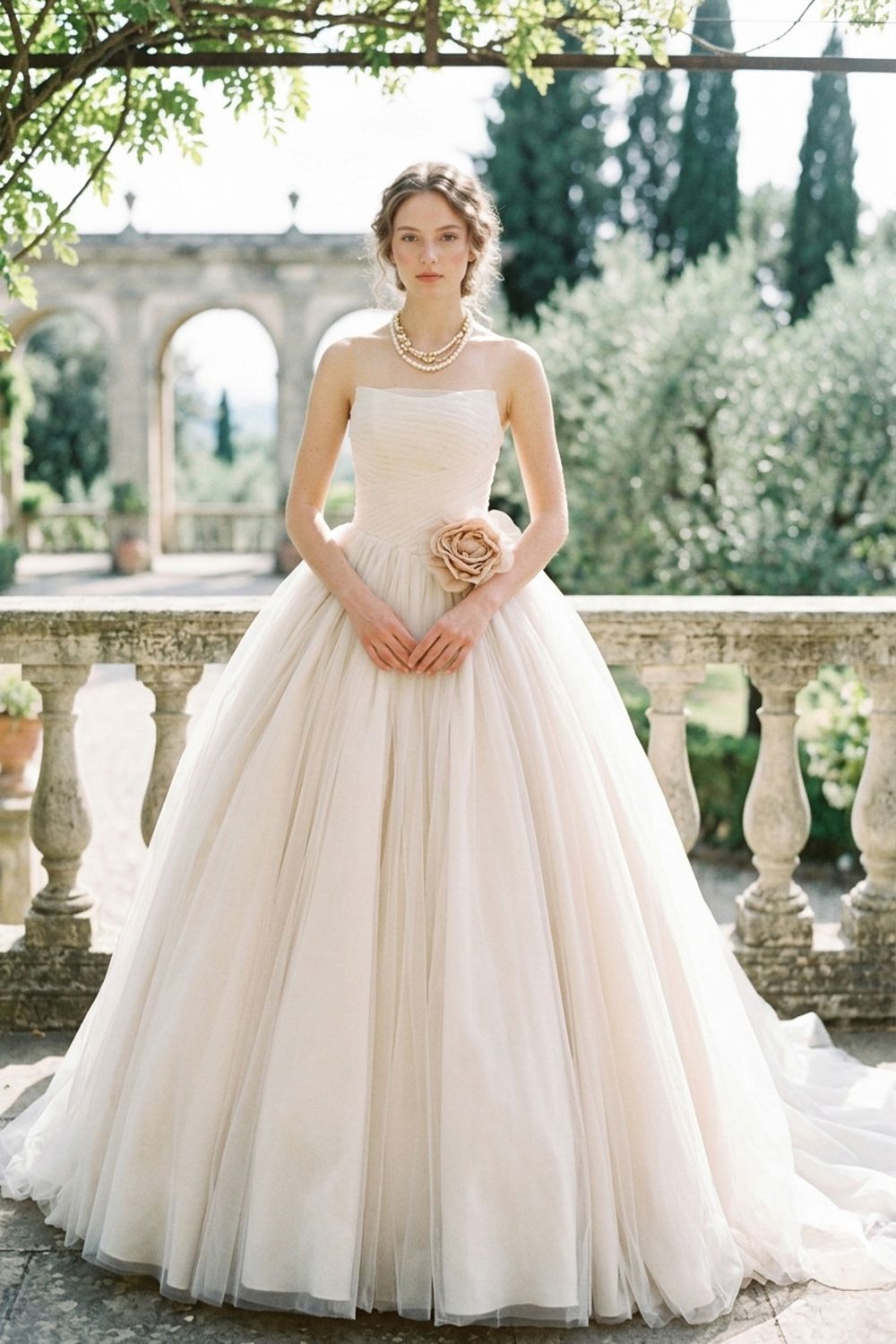 Strapless blush tulle ball gown wedding dress with ruched bodice and rose detail, photographed in an Italian garden.