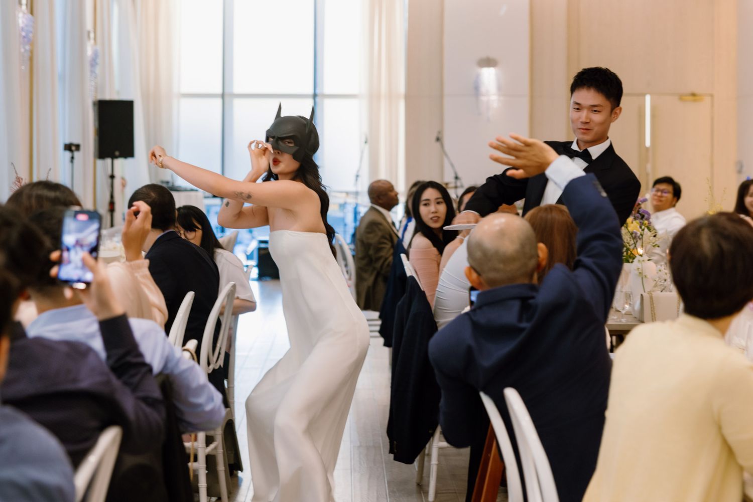 Bride in white gown and groom in tuxedo making a lively entrance at their wedding reception.