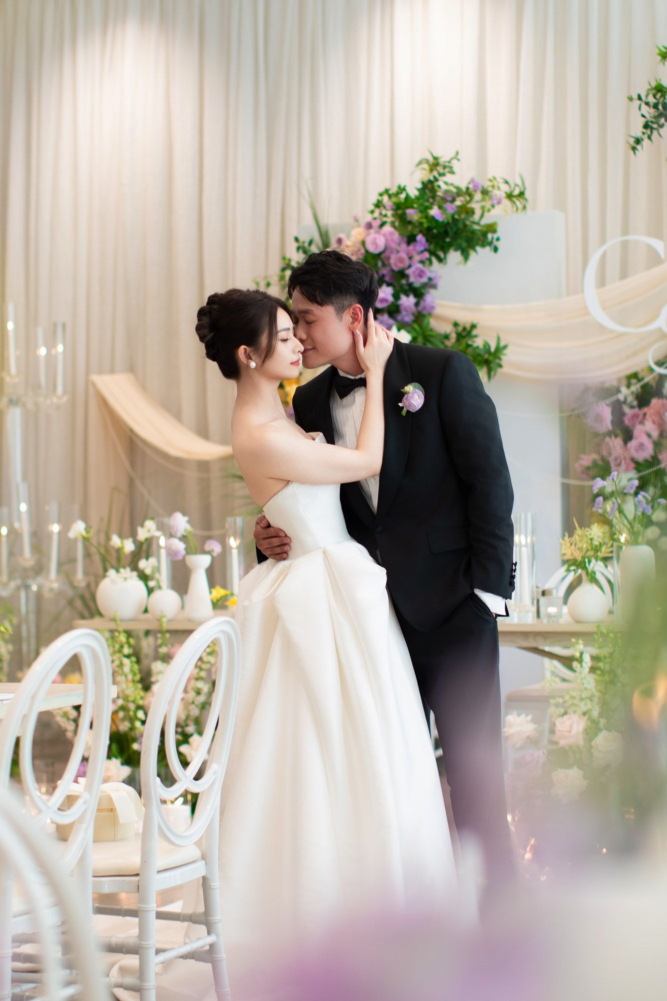 Bride and groom sharing an intimate moment in elegantly decorated wedding venue with flowers.