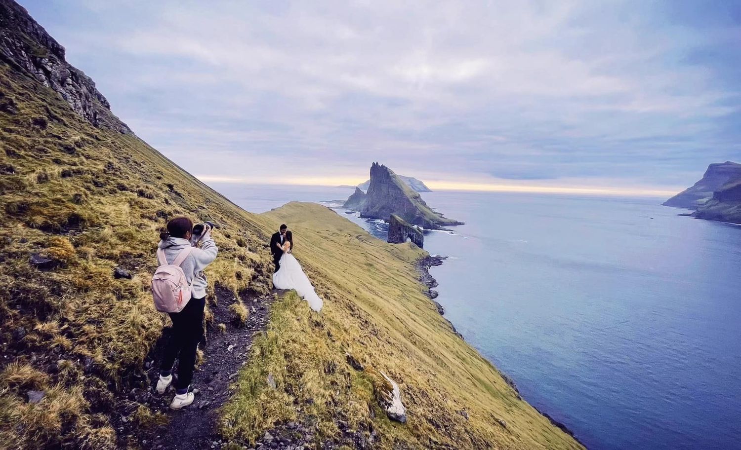 Wedding couple posing on dramatic coastal cliffs with ocean views in Iceland.