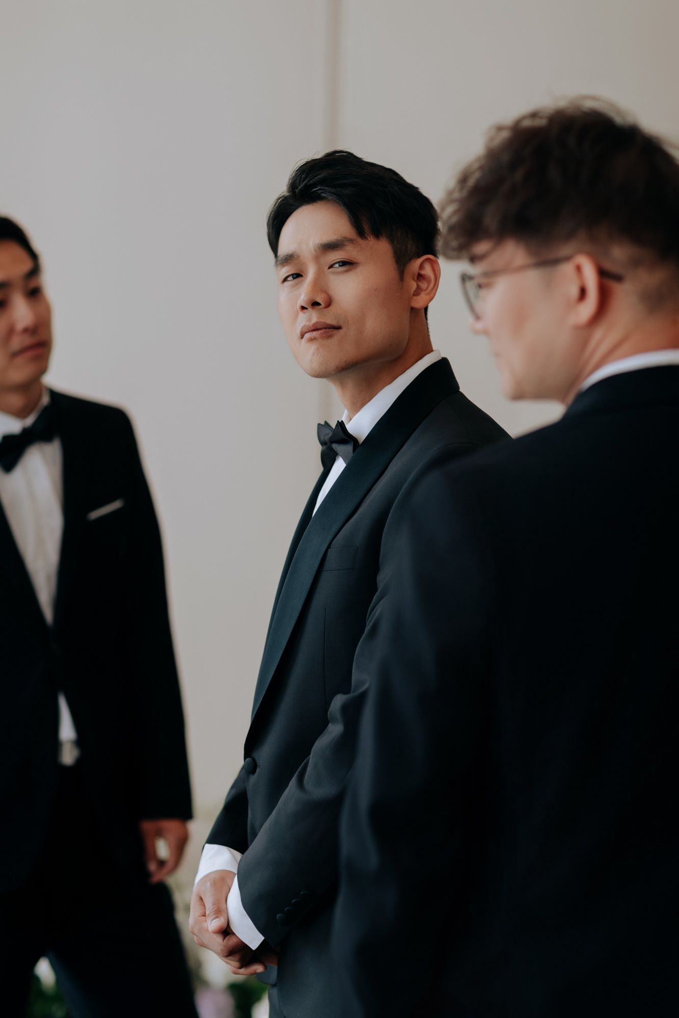 Handsome groom in black tuxedo standing attentively at wedding ceremony altar.