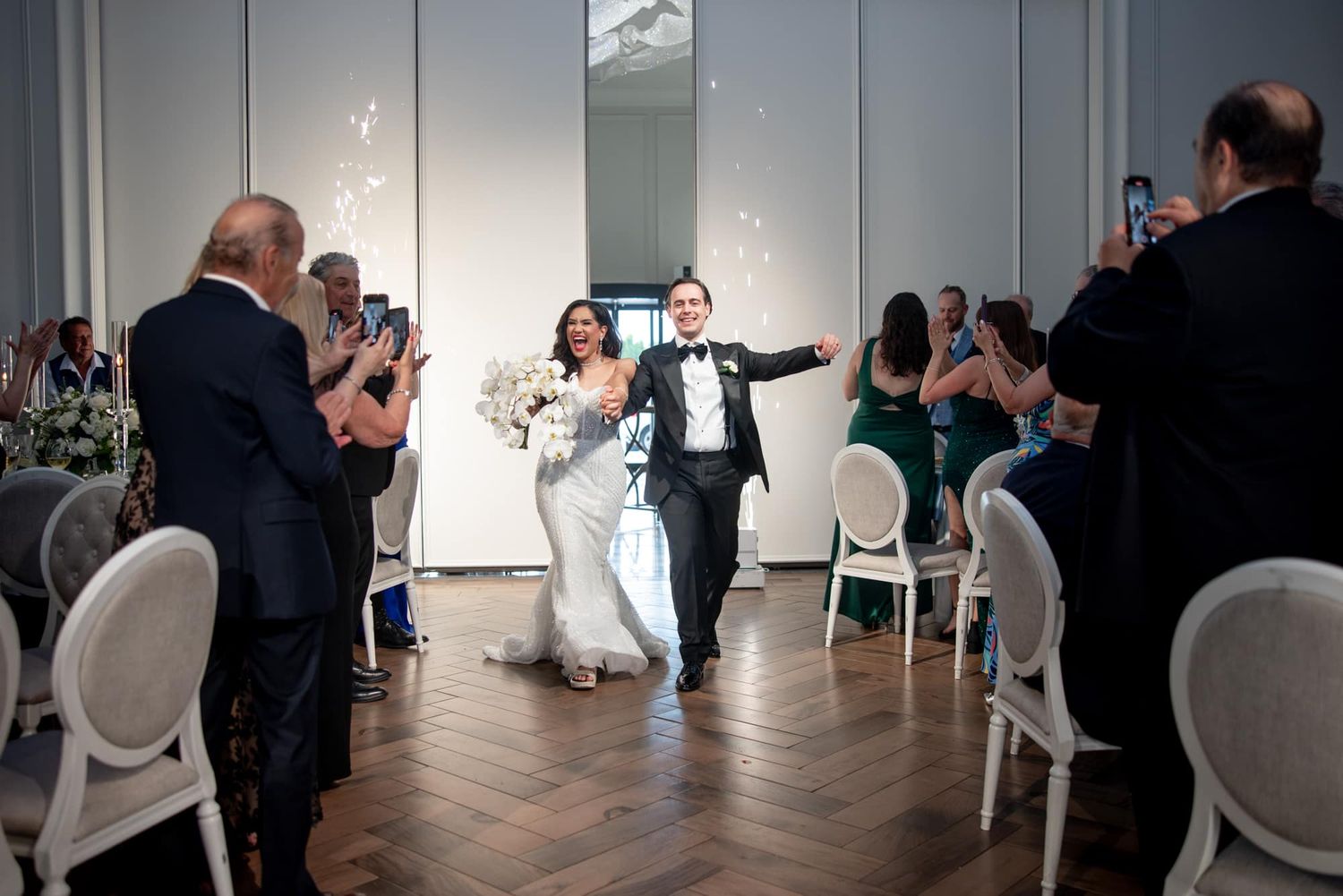 Bride and groom making a grand entrance with sparklers at their elegant wedding reception.