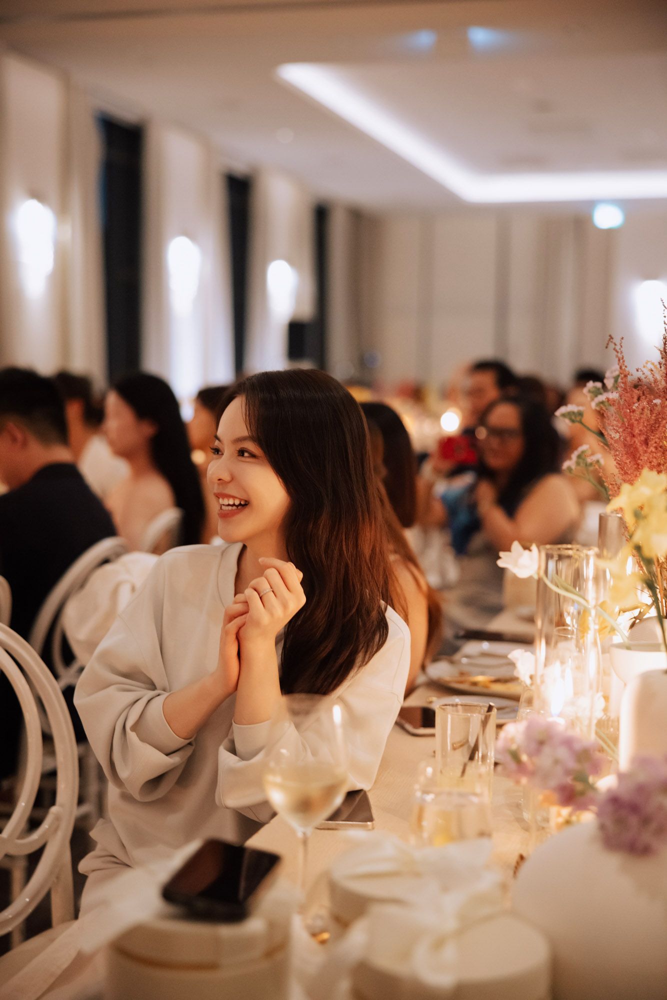 Joyful wedding guest laughs while seated at an elegant floral-decorated reception dinner table.