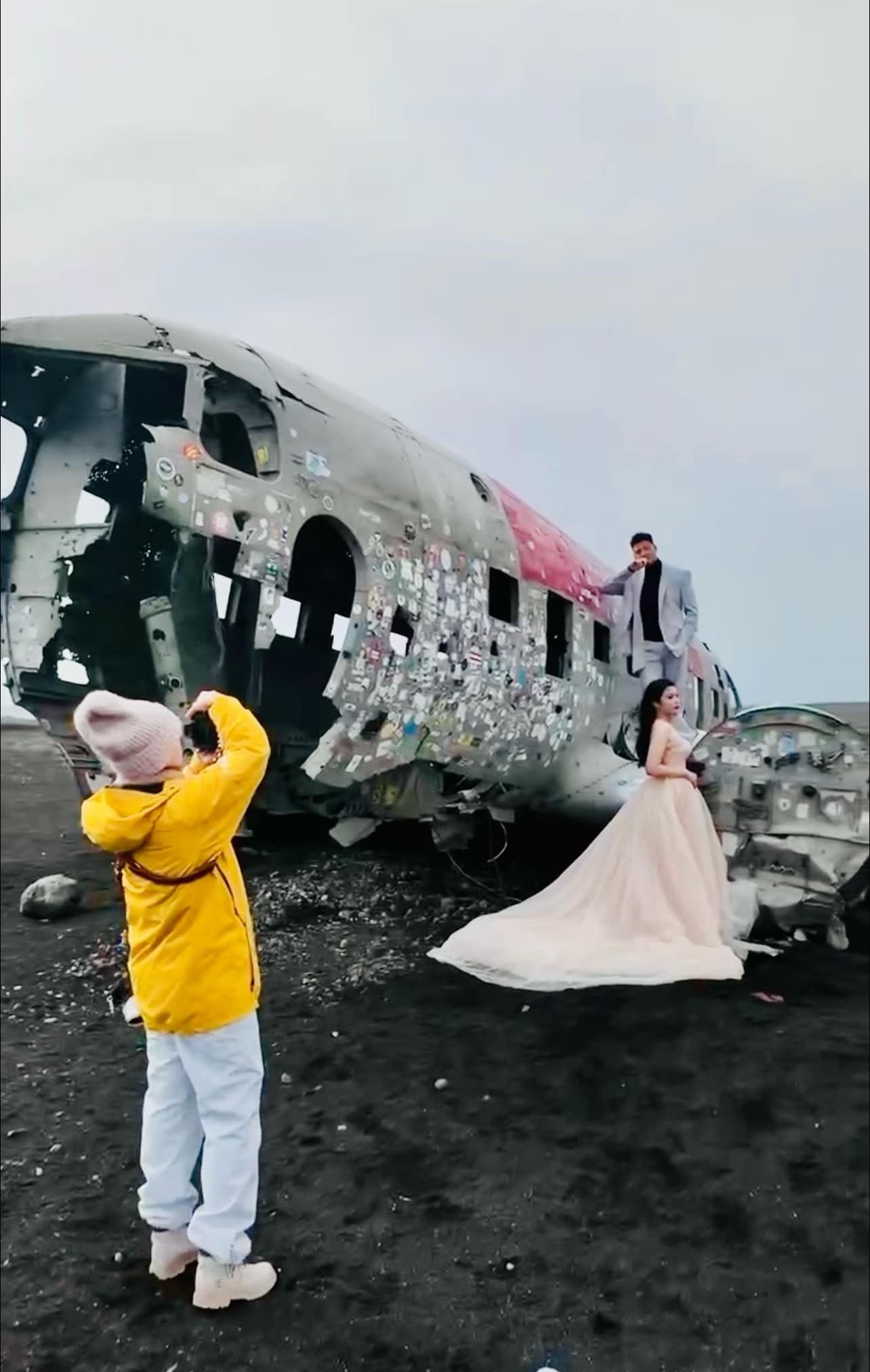 Photographer capturing bride and groom posing on iconic Iceland plane wreck.