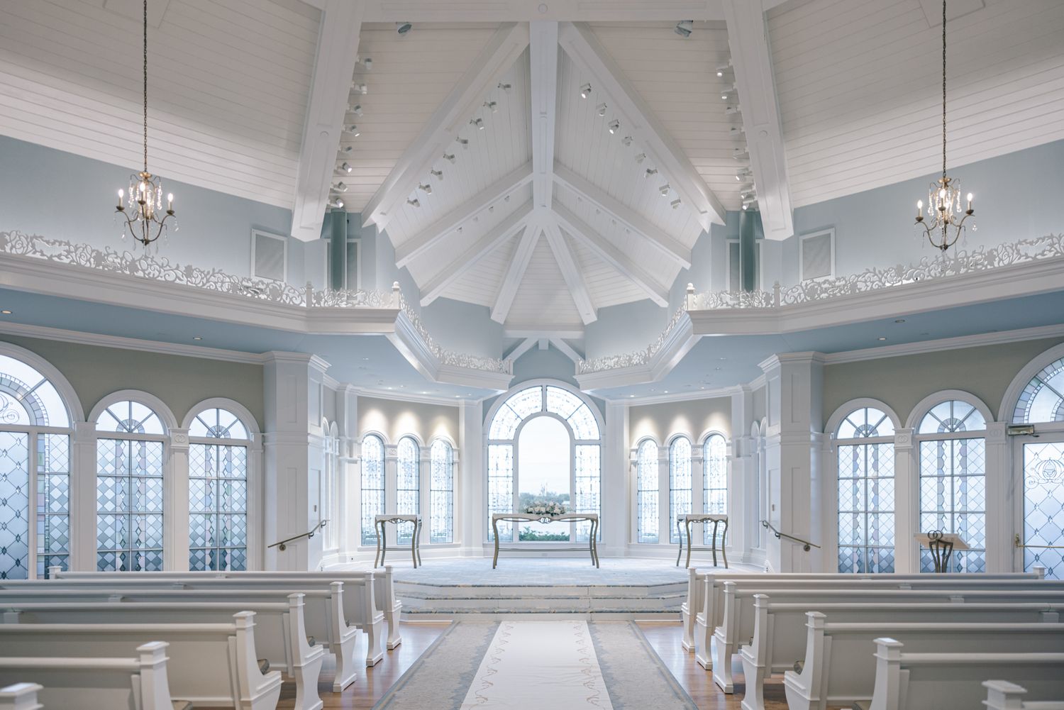 Elegant white Disney wedding chapel interior with vaulted ceiling and arched windows.