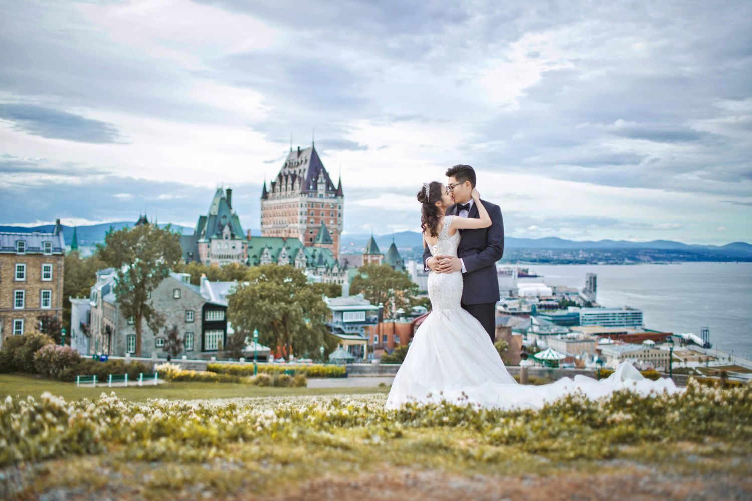 Bride and groom kiss in front of Chateau Frontenac castle in Quebec City, Canada on their wedding day.
