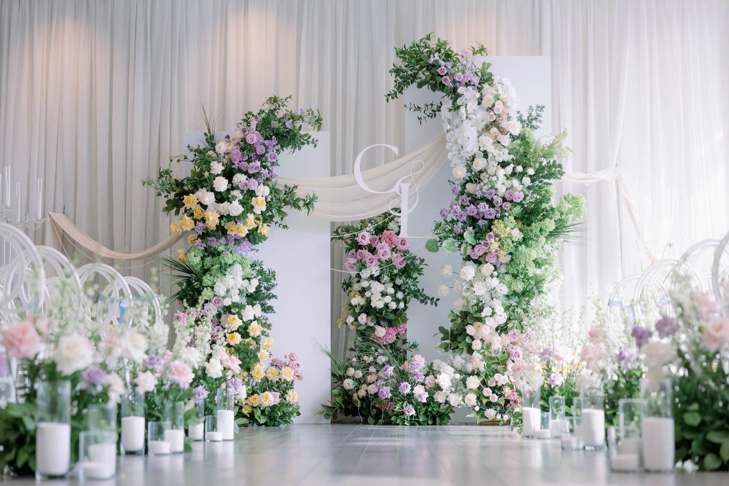 Wedding venue setup with floral arches, glass terrariums, and candles creating an elegant garden atmosphere.