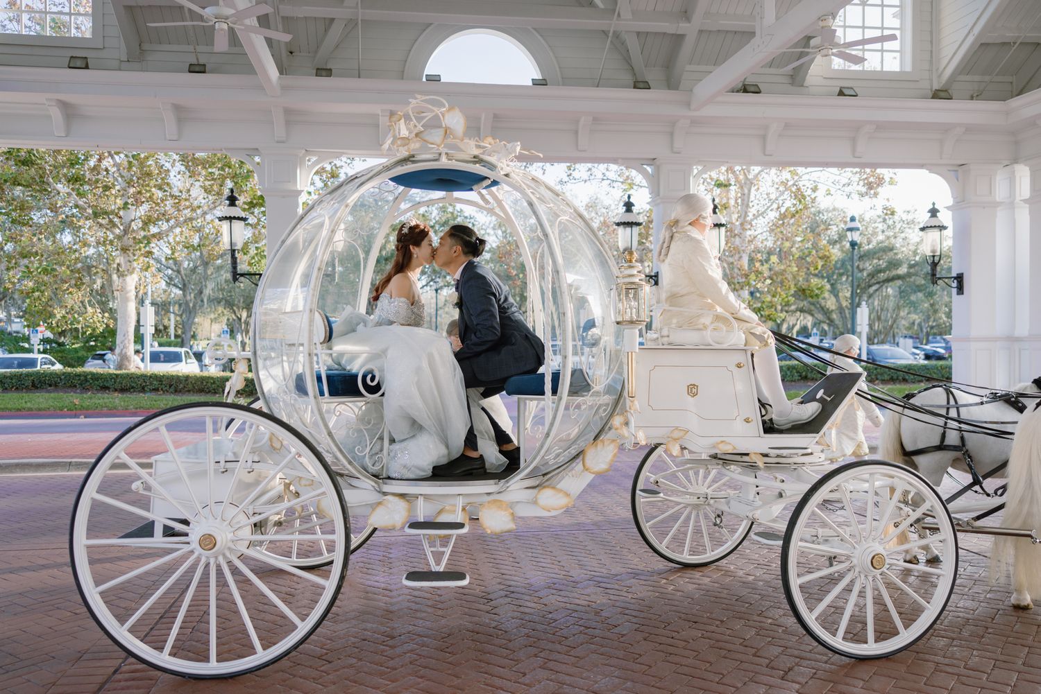 Bride and groom share a kiss inside a fairy-tale glass Cinderella carriage at a Disney wedding.