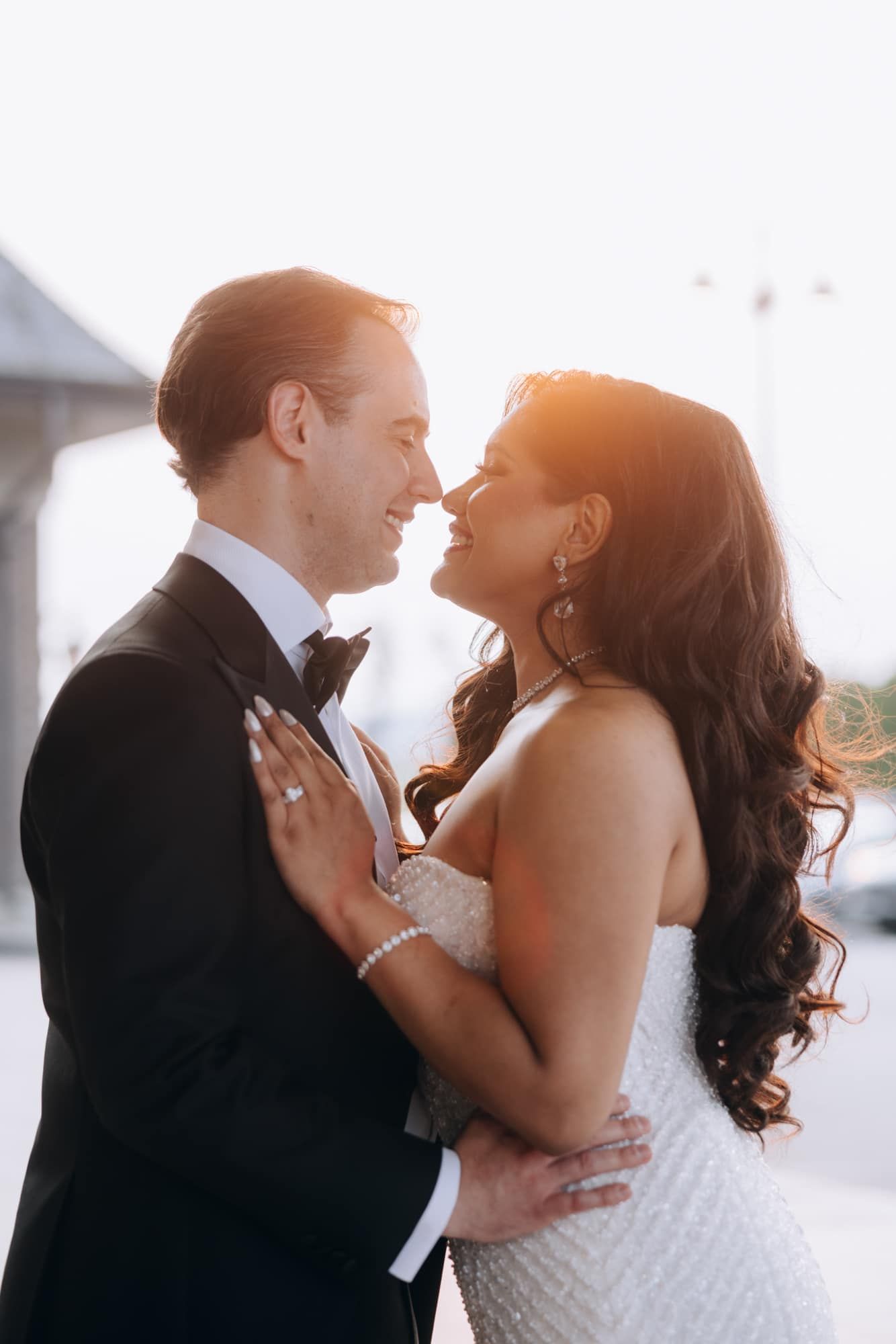 Bride and groom embrace intimately in golden sunset light during outdoor wedding portrait session.
