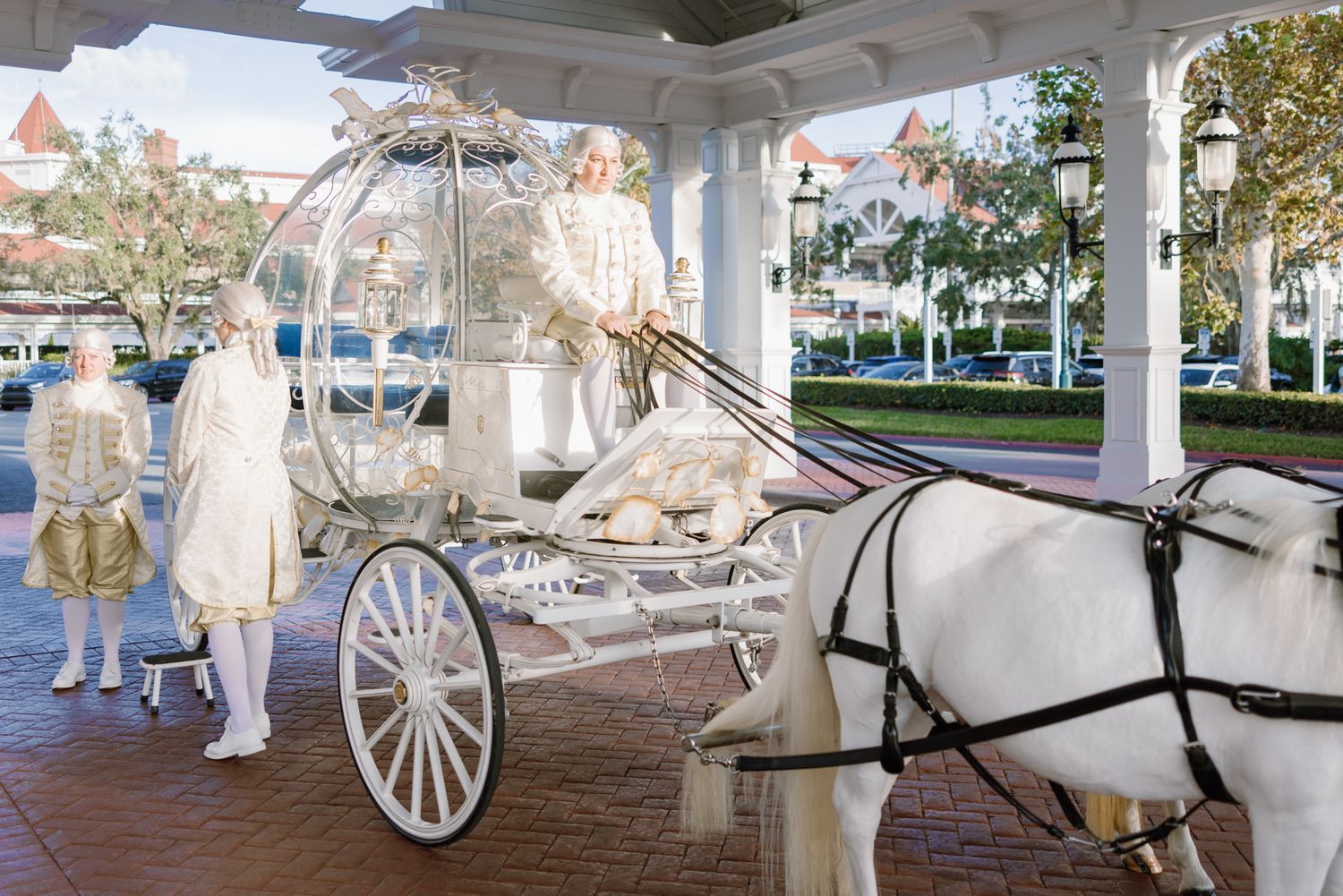 White Cinderella glass carriage with white horses and costumed attendants at Disney Grand Floridian Resort.