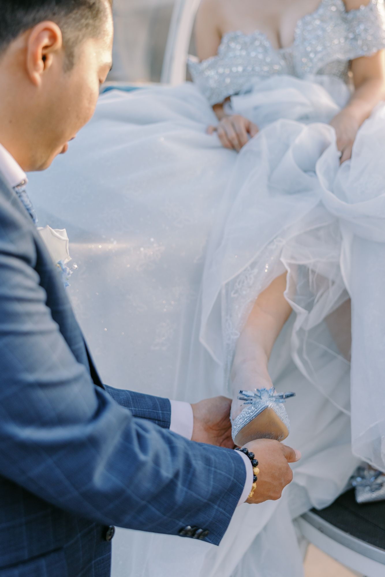 Groom tenderly places a glass slipper on the bride's foot during a Disney-themed wedding ceremony.