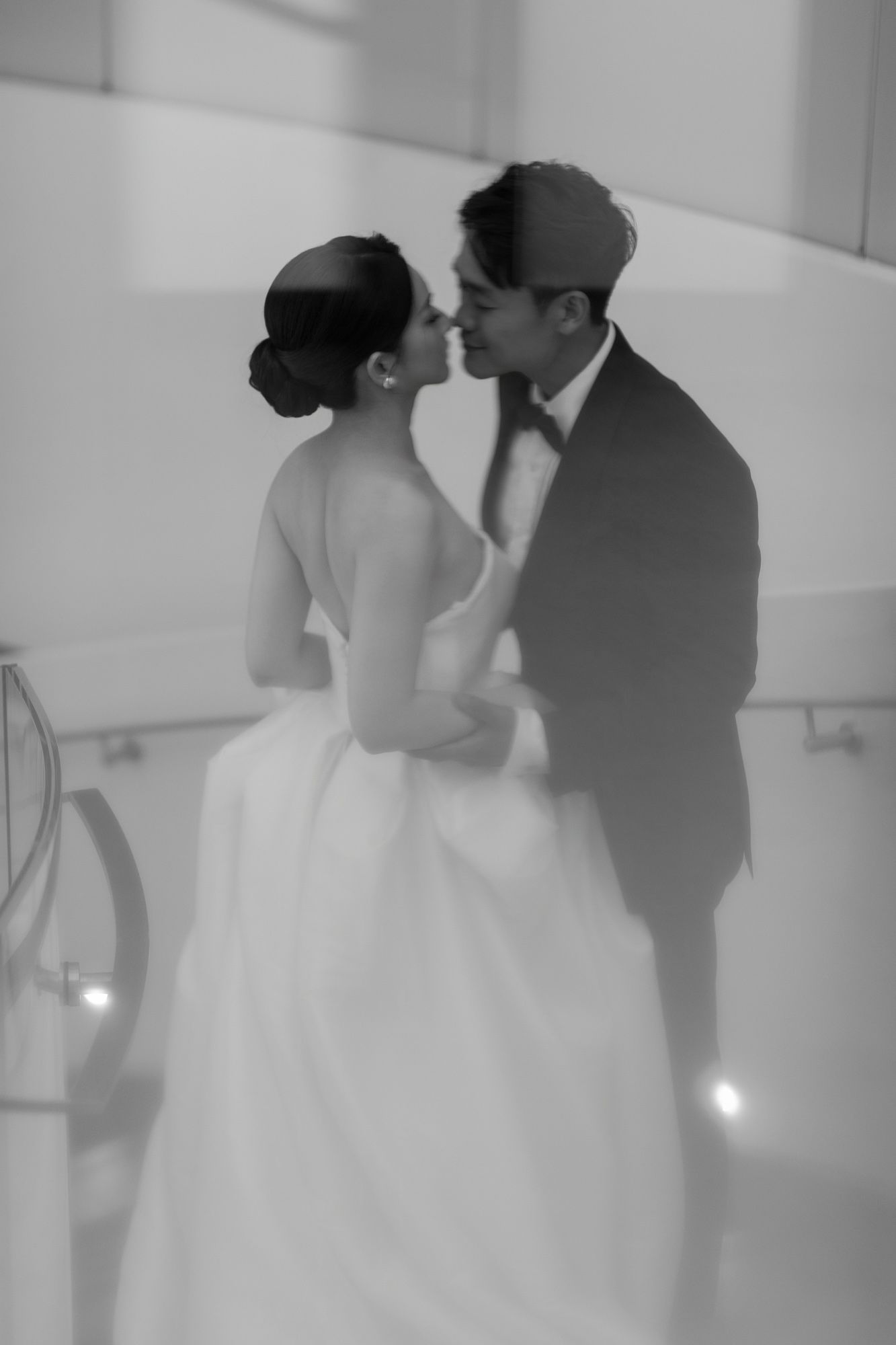 Black and white romantic photo of bride and groom sharing a tender kiss at their wedding.