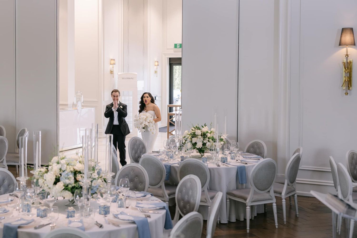 Bride and groom make grand entrance into elegant blue and white wedding reception hall.