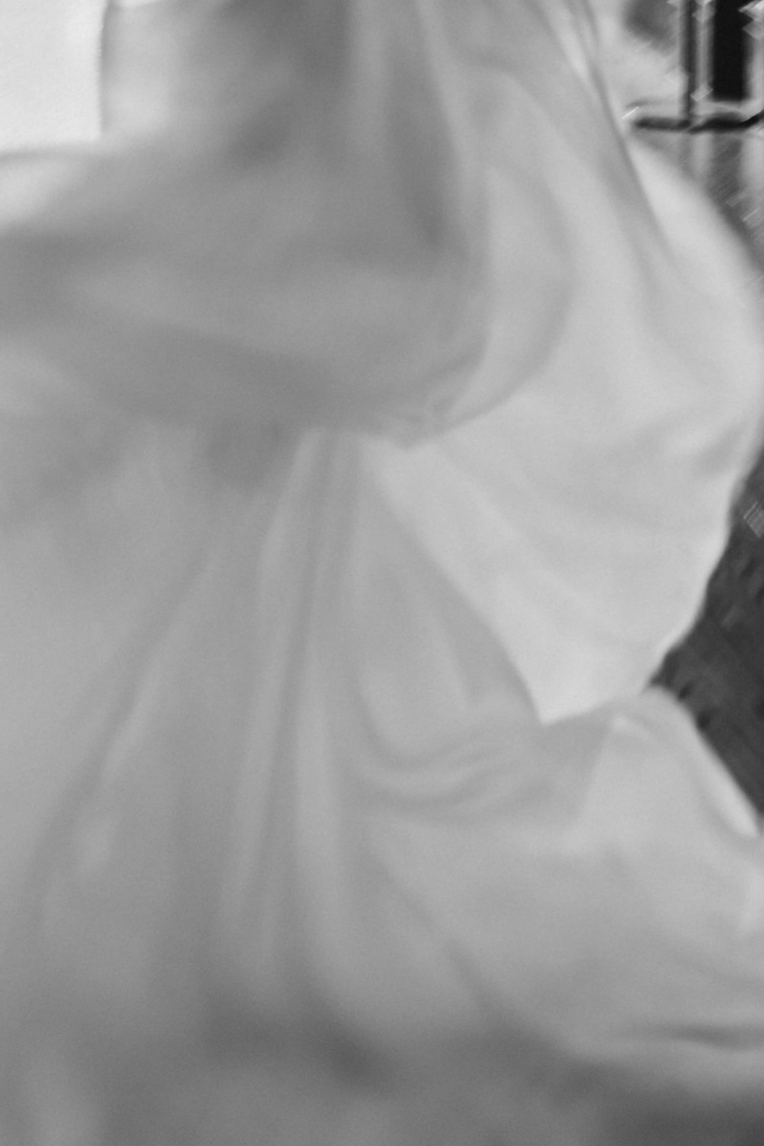 Artistic black and white blurred motion shot of a flowing white wedding gown.