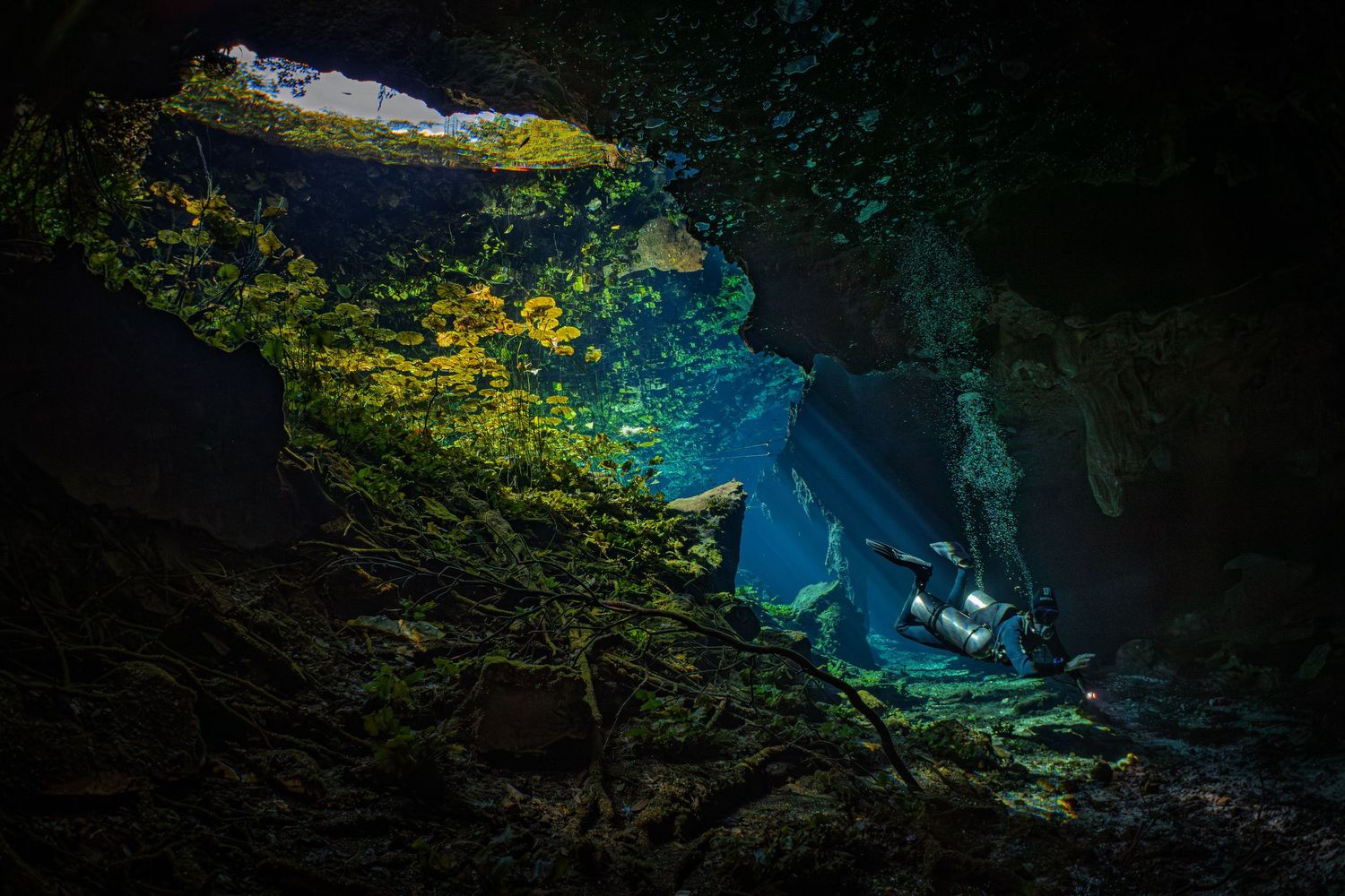 A series of dark cave passages illuminated by turquoise blue water glowing mysteriously in the underground chambers.