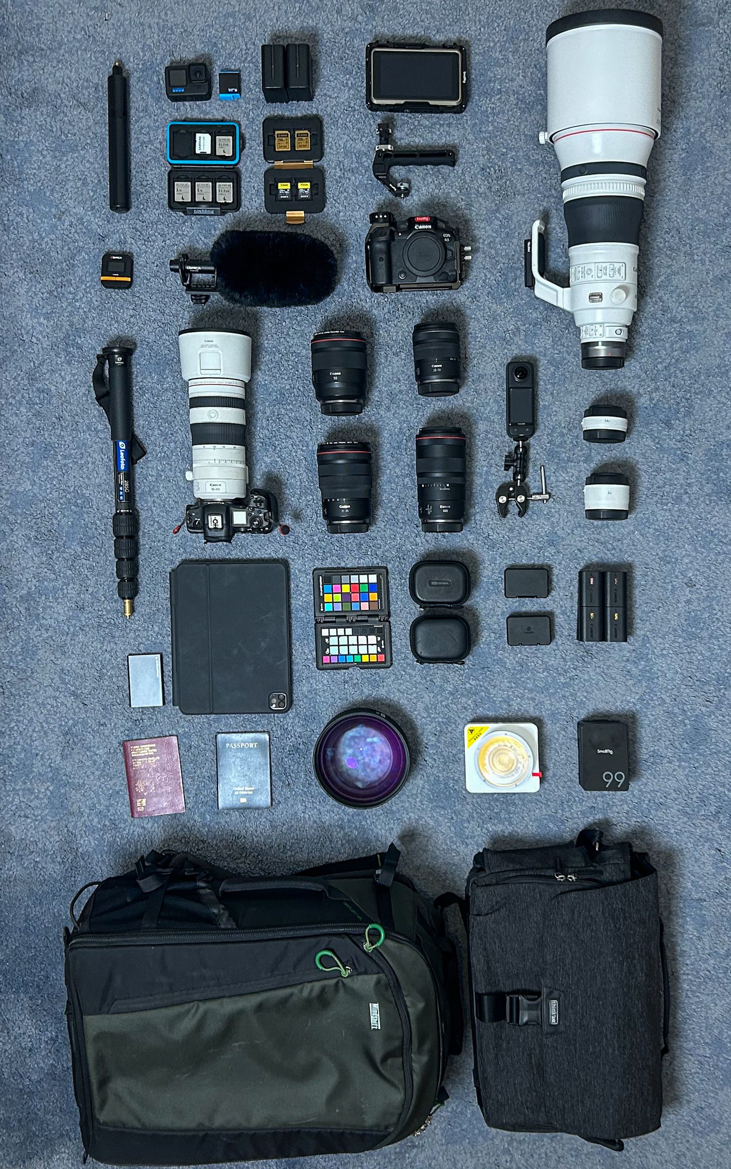 Professional camera equipment and accessories neatly arranged on a gray surface showing lenses, bags, and photography tools.