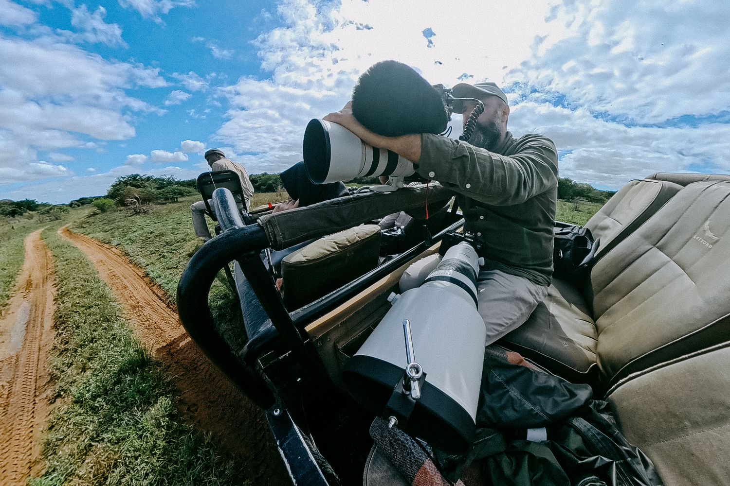 Professional camera gear and long telephoto lenses mounted on equipment for wildlife photography on a dirt road.