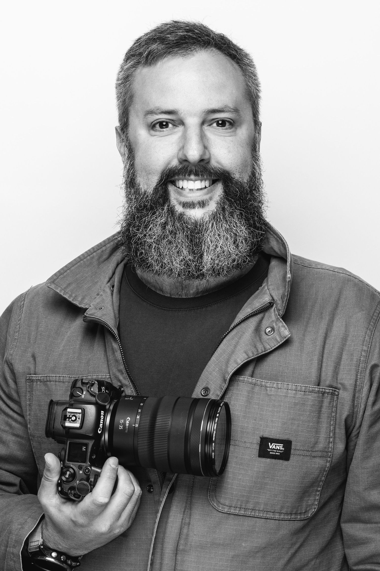 Portrait series of photographer holding professional camera equipment against white background.