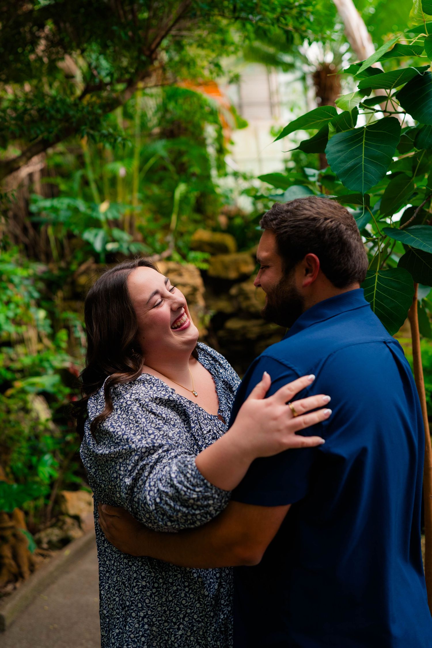 Joyful couple embracing and laughing together in tropical botanical garden setting.