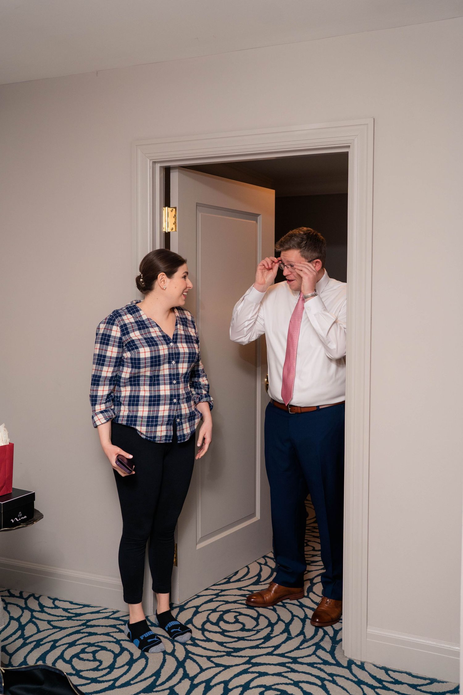 Bride and groom sharing a joyful moment in a hotel doorway during wedding preparations.