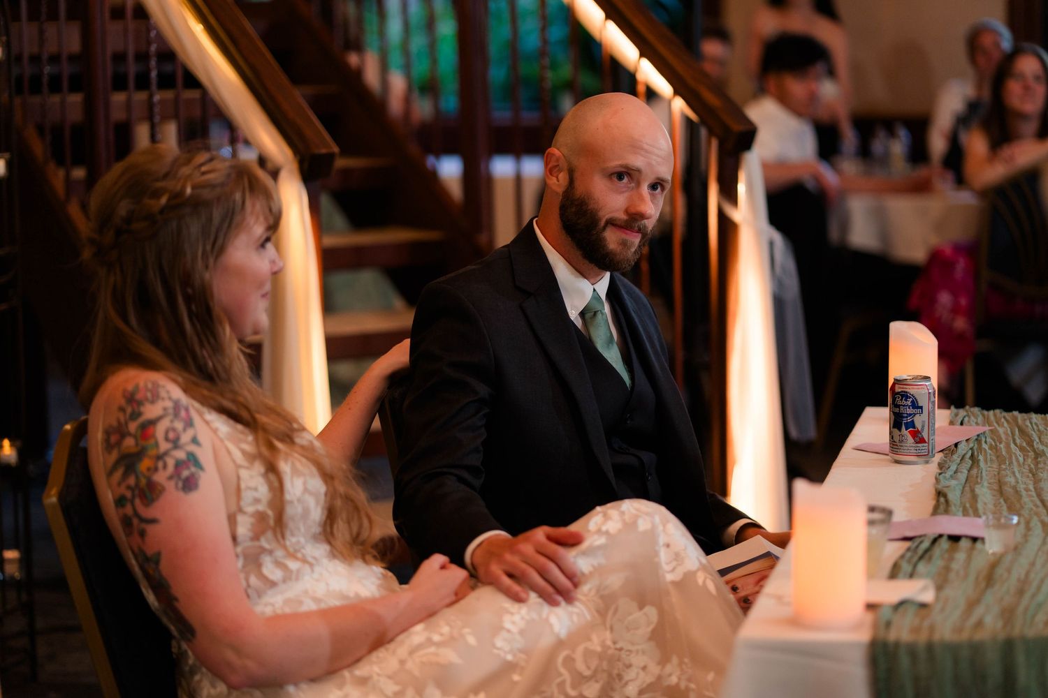 Bride and groom sitting together at sweetheart table during wedding reception.