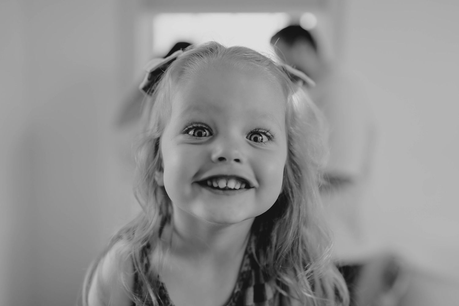 Black and white portrait of a smiling young girl with long hair looking up joyfully.