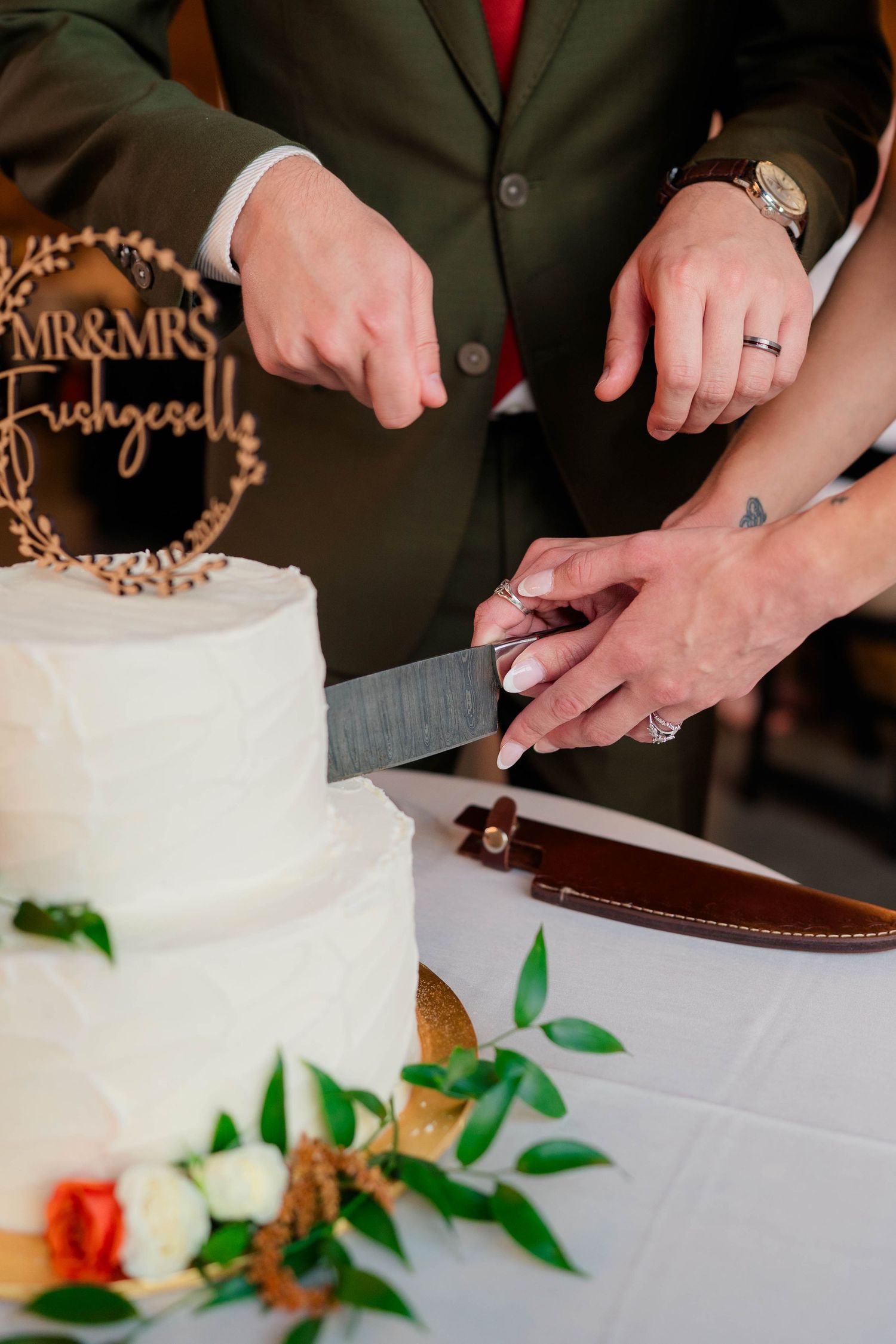 Newlyweds cutting white tiered wedding cake with Mr and Mrs Frishgesell wooden topper.