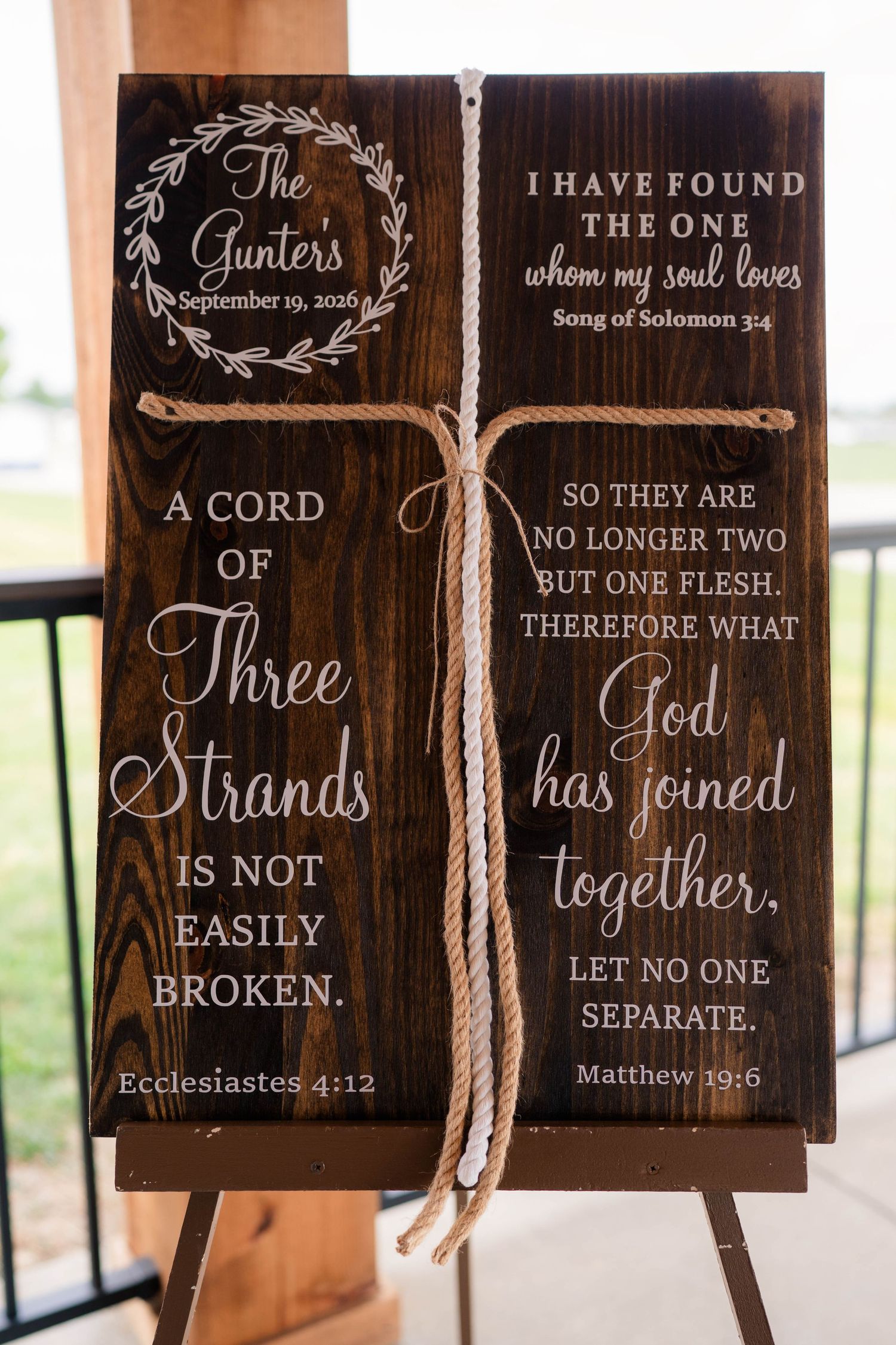 Rustic wooden wedding sign featuring Bible verses about marriage and a cord of three strands.