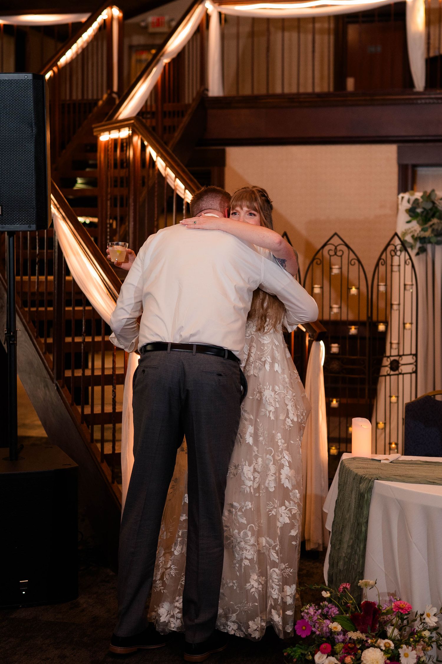 Bride and groom sharing an emotional embrace near a staircase during their wedding reception.