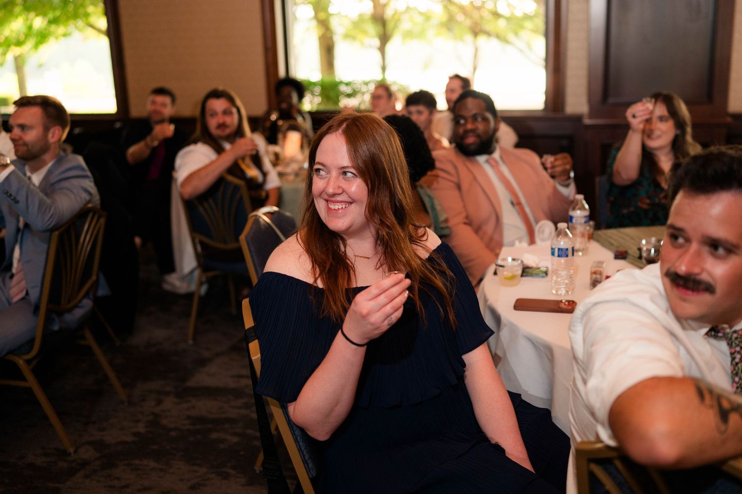 Wedding guests clapping and smiling during reception celebration in elegant banquet hall.
