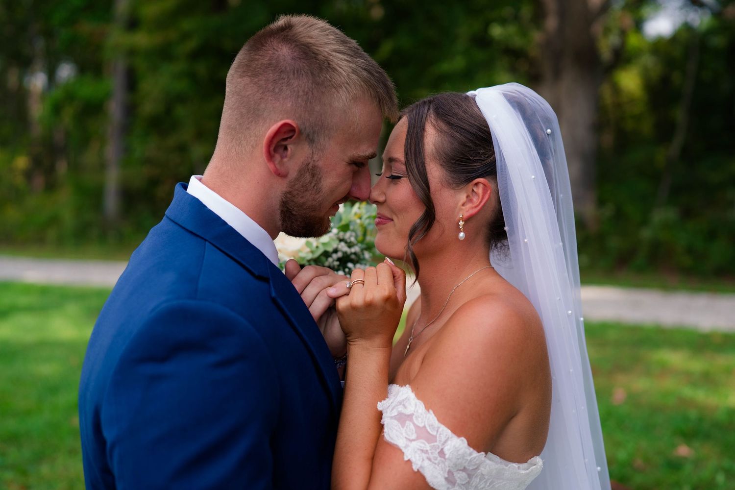 Bride and groom sharing an intimate forehead touch moment outdoors on their wedding day.