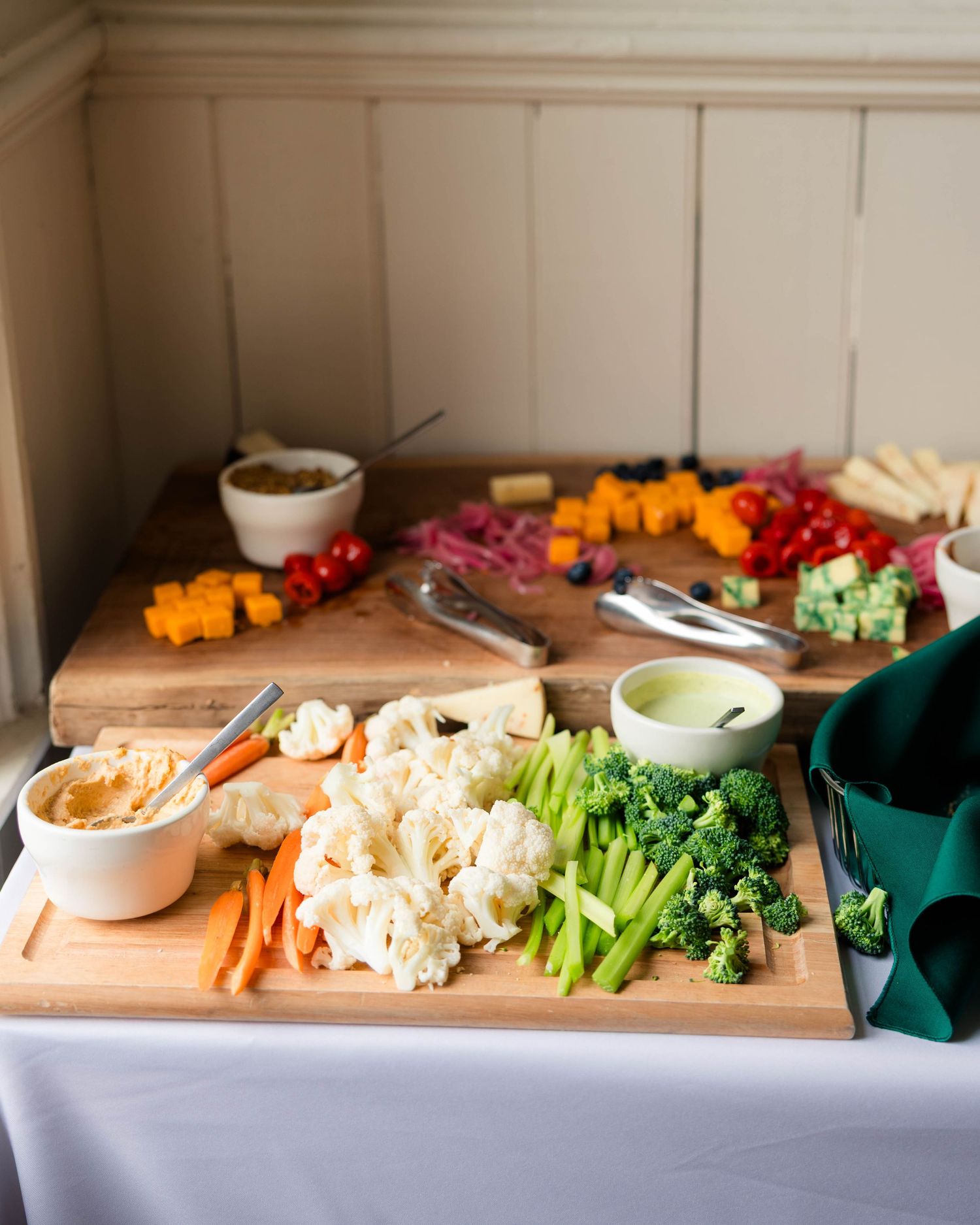 Elegant wedding charcuterie board with vegetables, hummus, and colorful garnishes.