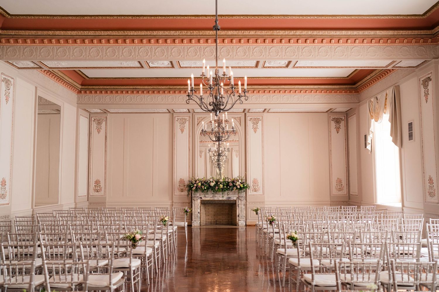 Elegant ballroom wedding ceremony setup with chiavari chairs, chandelier, and floral altar.