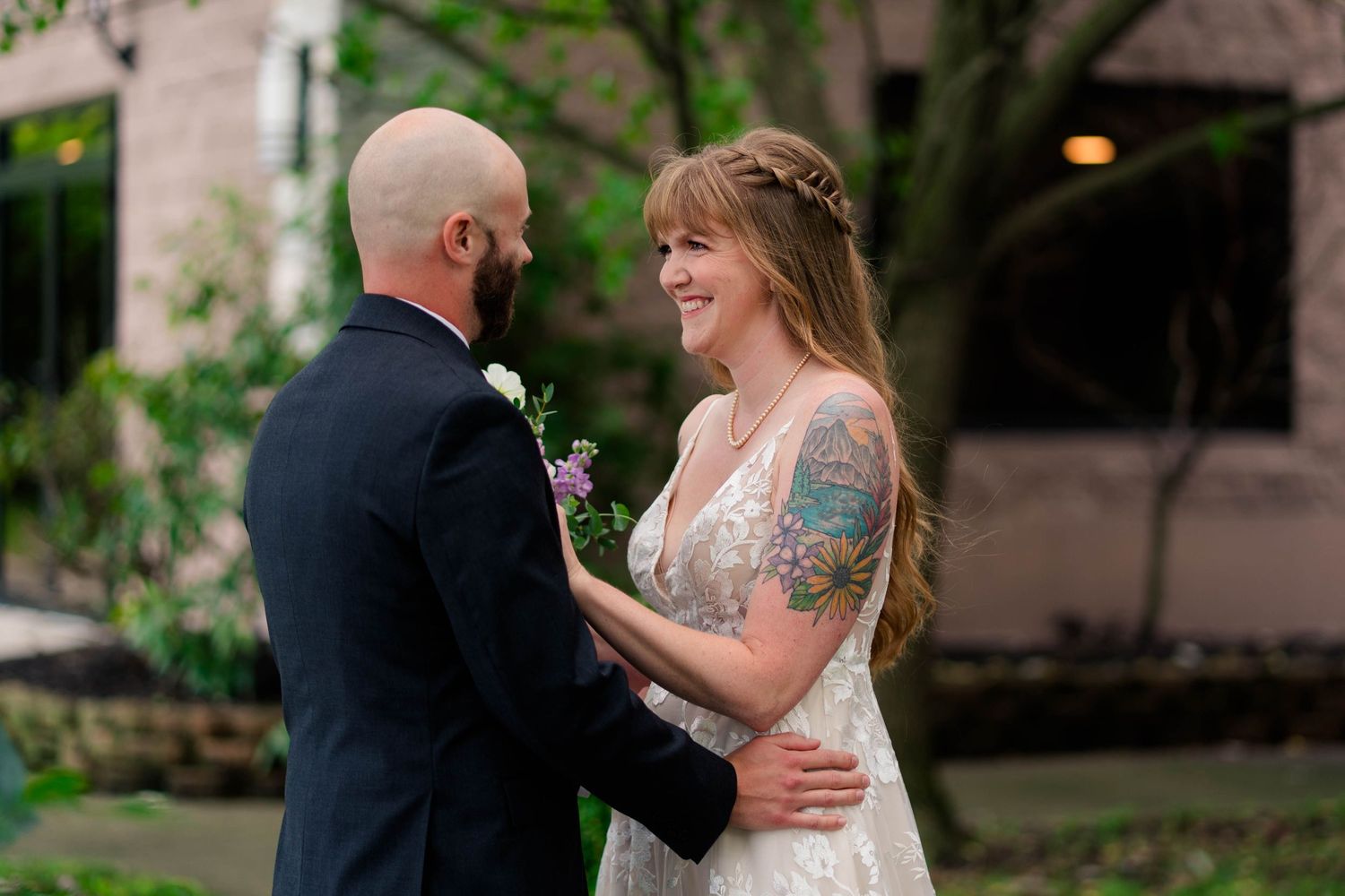 Bride and groom share emotional first look moment, smiling at each other in garden setting.