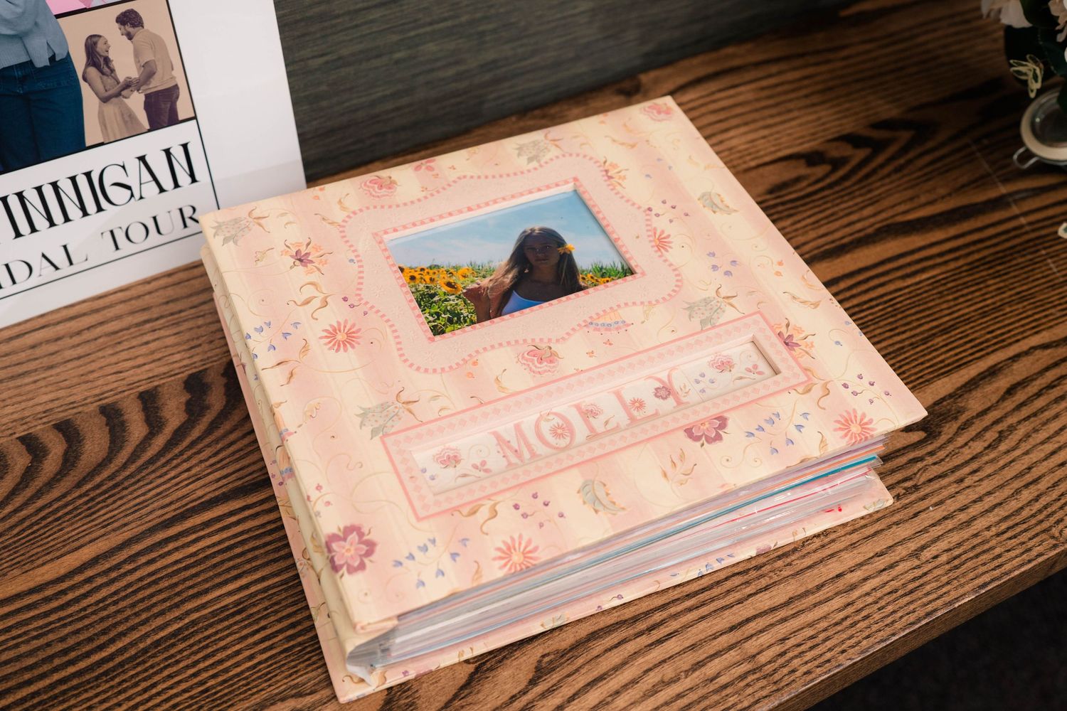 Pink floral photo album featuring a dog portrait displayed on a wooden surface.