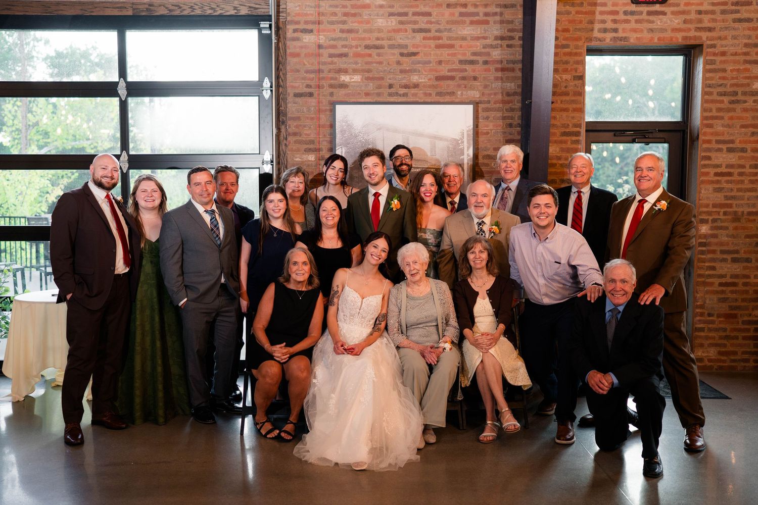 Wedding party and family pose for formal group portrait with bride and groom at reception.