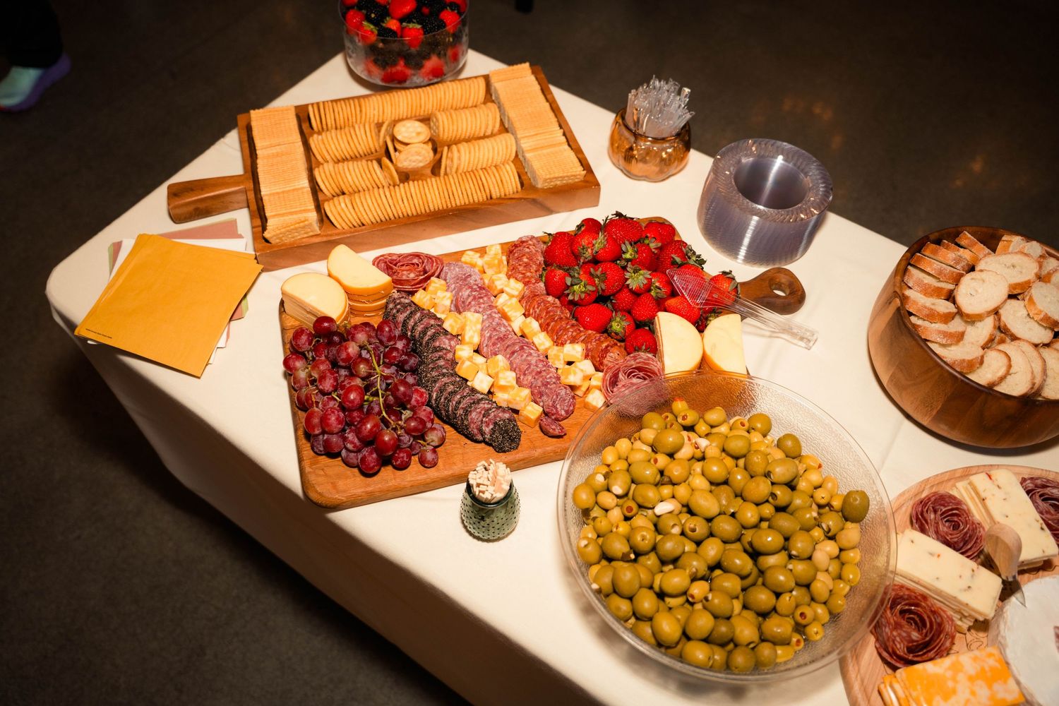 Elegant charcuterie board with olives, strawberries, meats, cheeses, and crackers at a wedding reception.